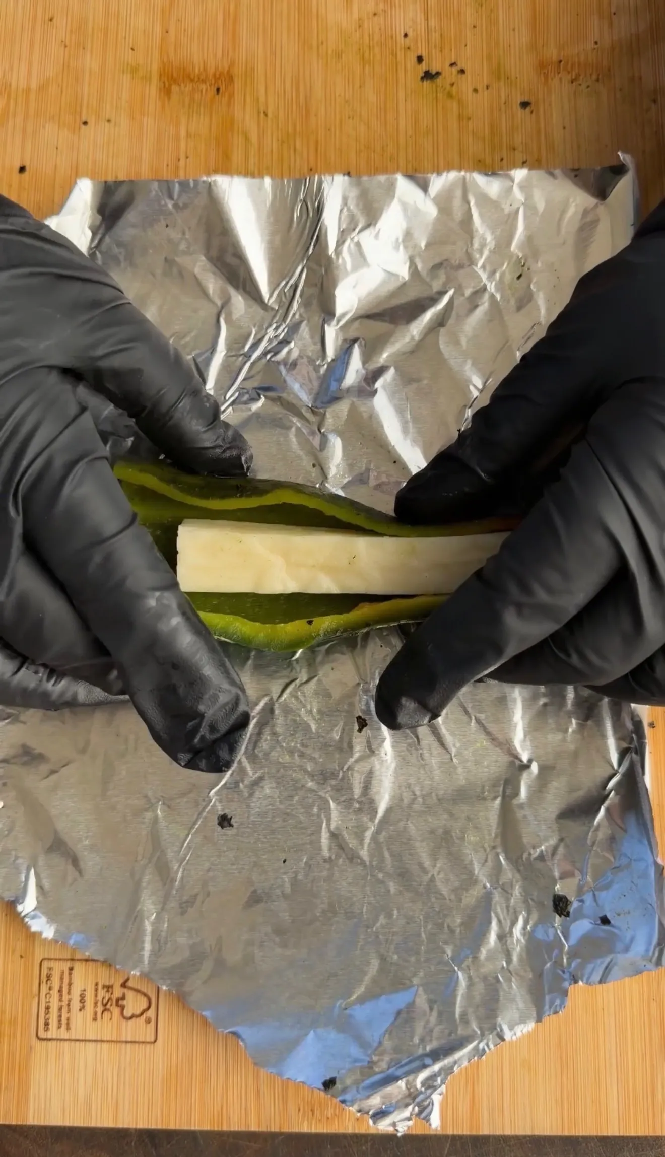 Roasted poblano peppers wrapped in foil during prep