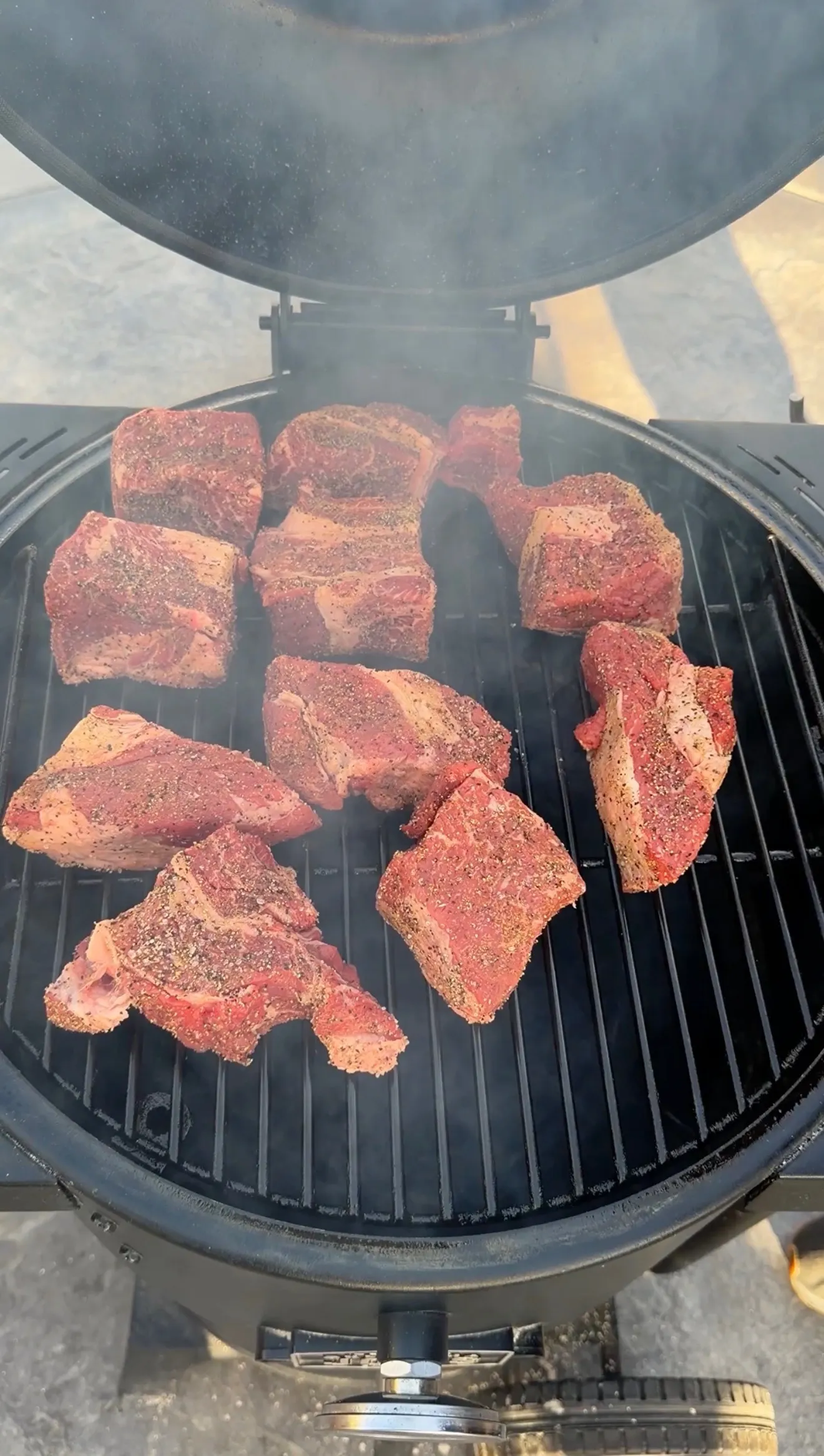 Seasoned beef chunks smoking on round grill