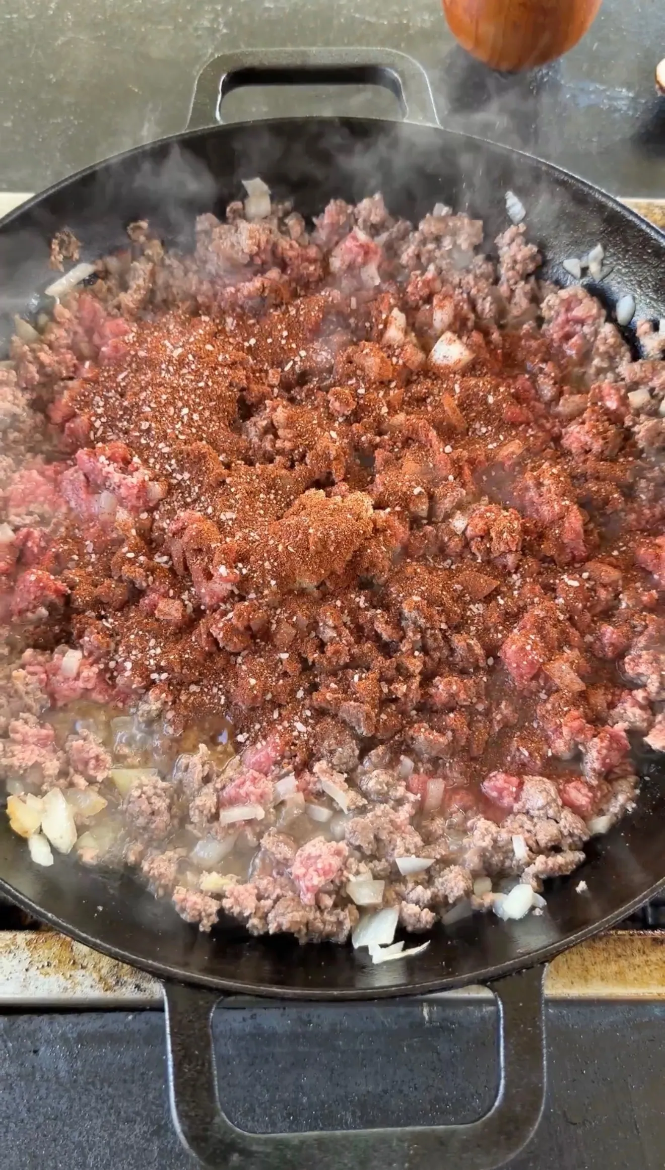 Seasoned ground beef cooking in cast iron skillet