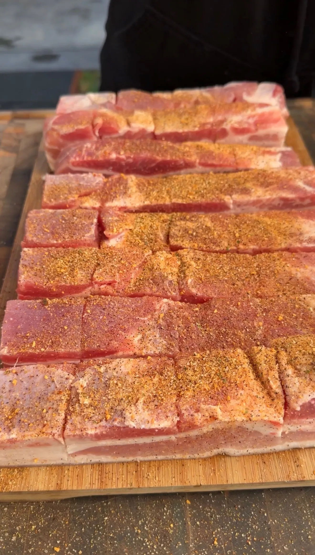 Seasoned pork belly slices on wooden cutting board
