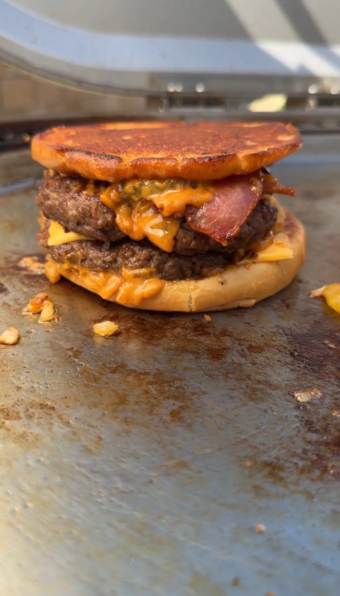 Bacon cheeseburger patty melt with double beef patties, melted cheese, and crispy bacon on a hot griddle