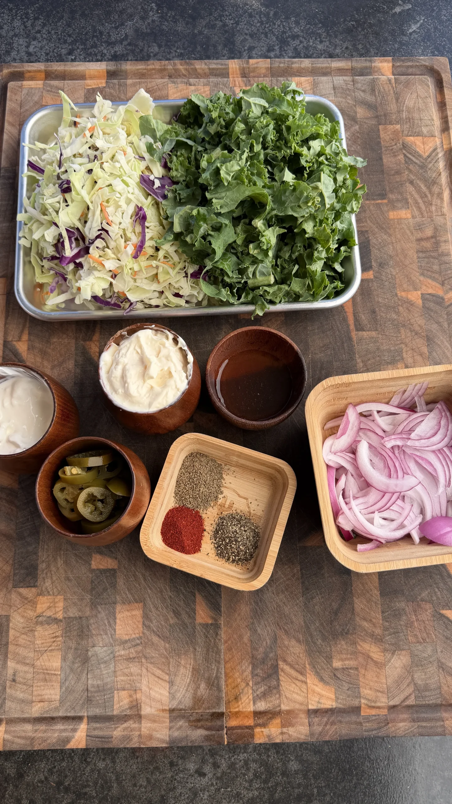Fresh salad greens, coleslaw mix, sliced red onions, spices and condiments arranged for barbecue brisket sides