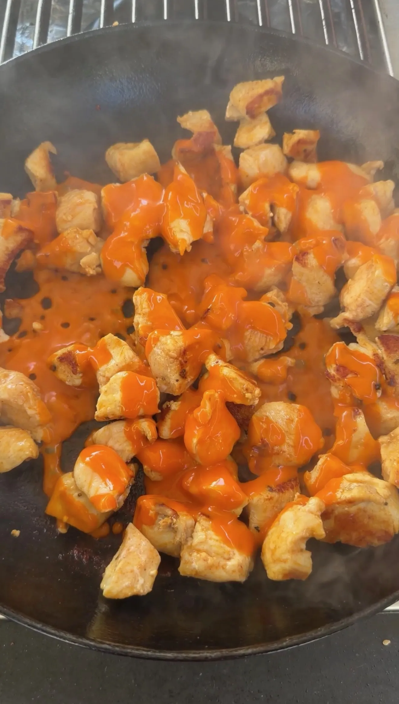 Buffalo chicken cooking in cast iron pan