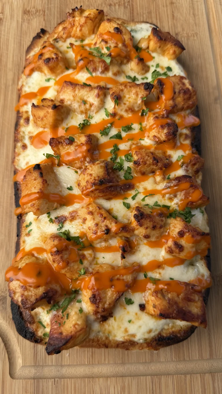 Buffalo chicken ranch flatbread topped with melted cheese, grilled chicken, orange buffalo sauce drizzle and fresh herbs