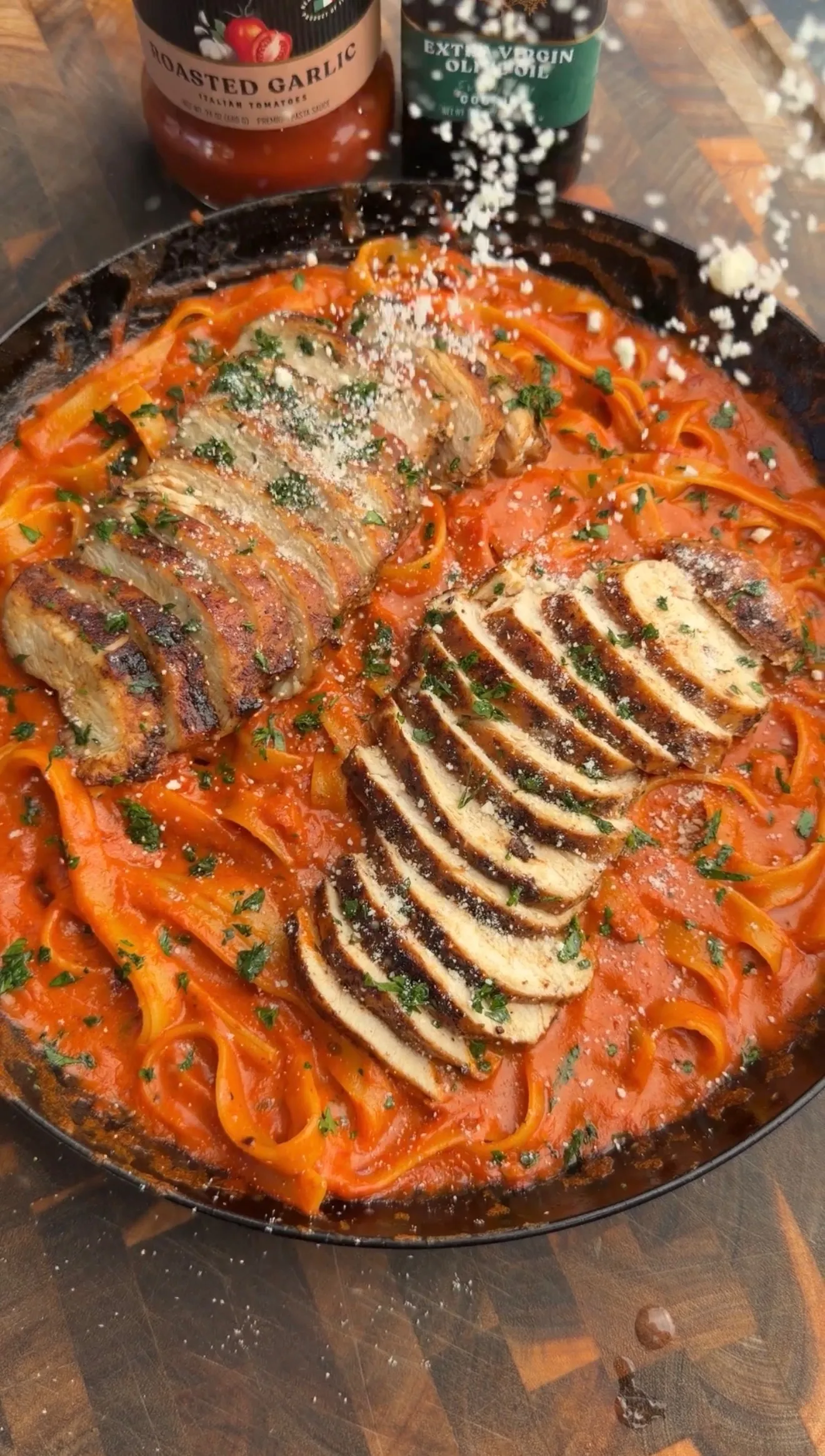 Cajun chicken fettuccine pasta with sliced grilled chicken, bell peppers, and herbs in a black cast iron skillet