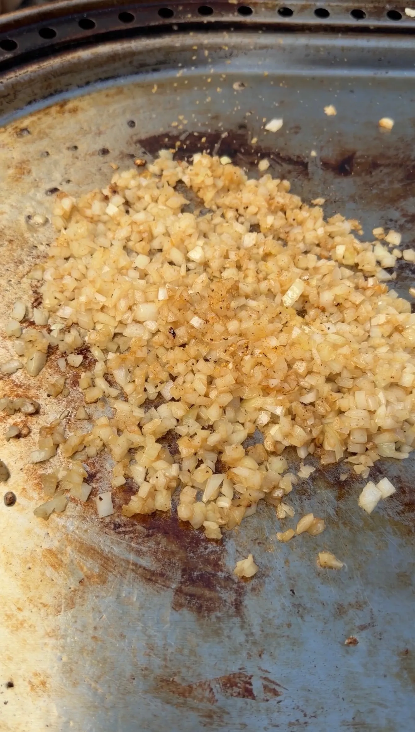 Golden caramelized diced onions cooking in a well-seasoned cast iron skillet for bacon cheeseburger patty melt