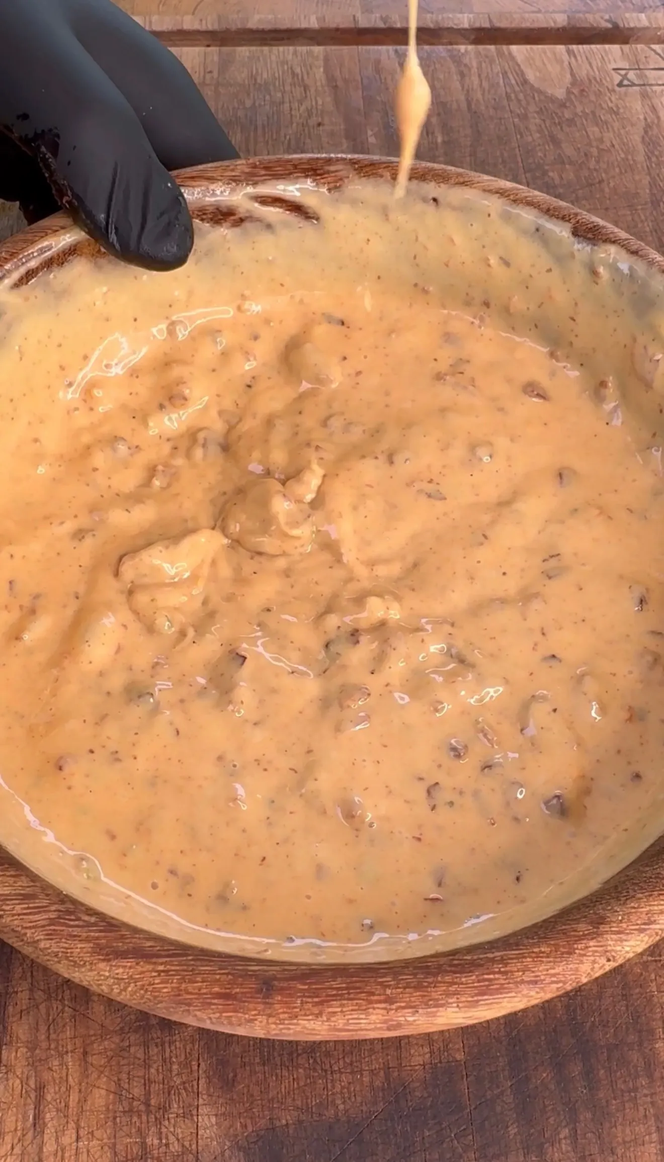 Creamy baconnaise sauce in wooden bowl being mixed