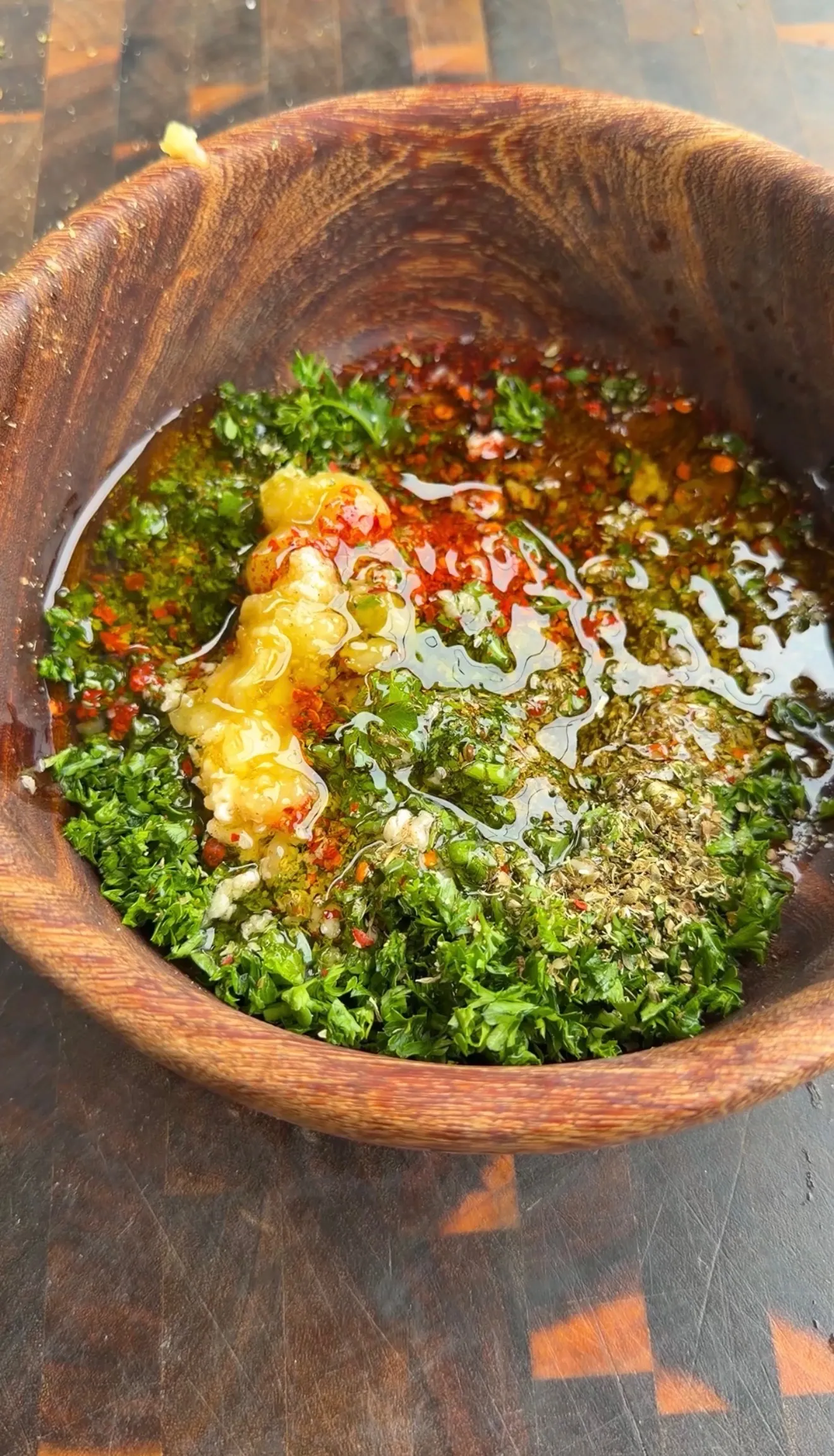 Fresh green herb sauce with garlic and spices being prepared in a wooden mortar and pestle
