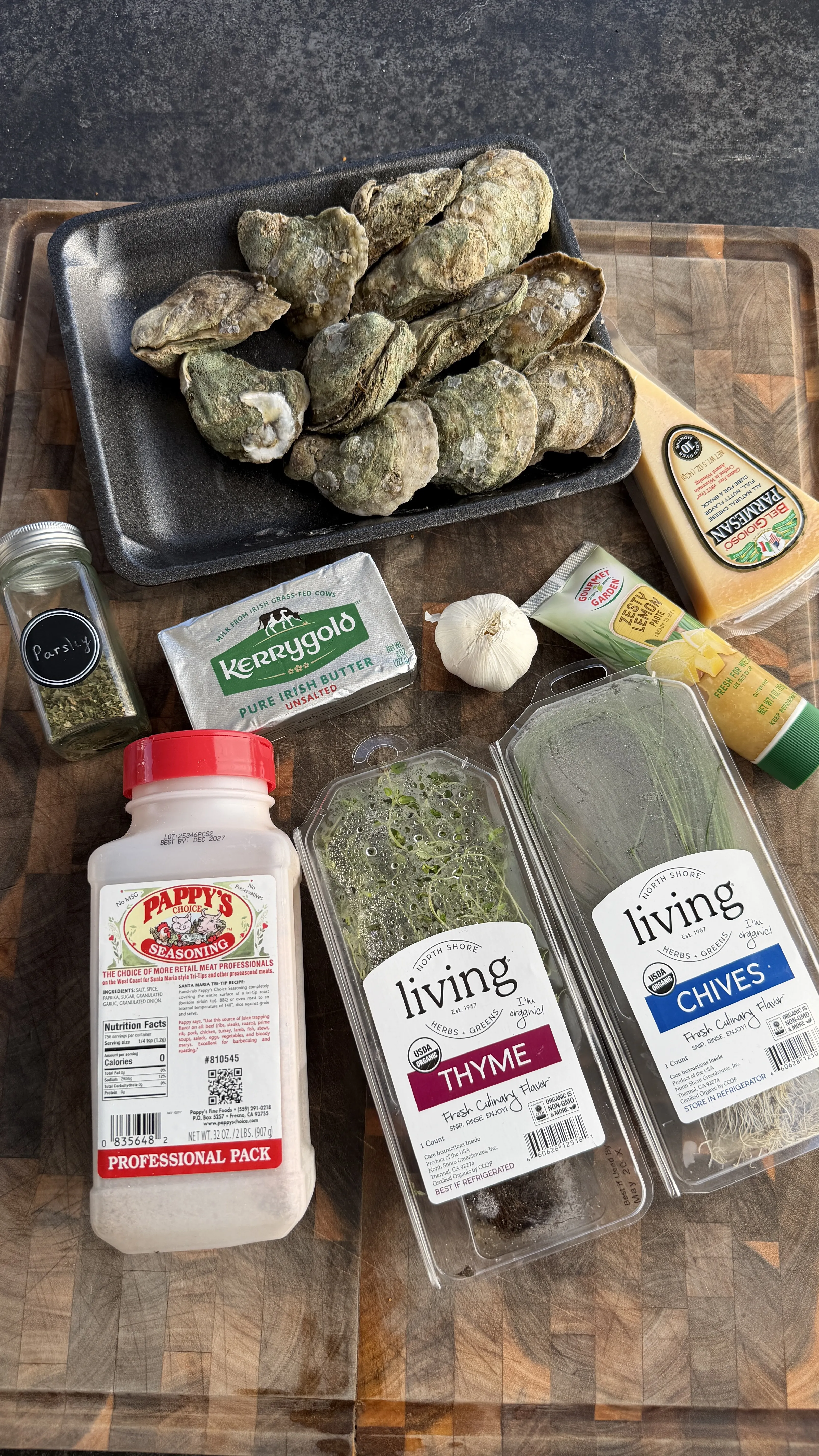 Fresh oysters arranged with garlic, herbs, butter, and cheese ingredients prepared for grilling