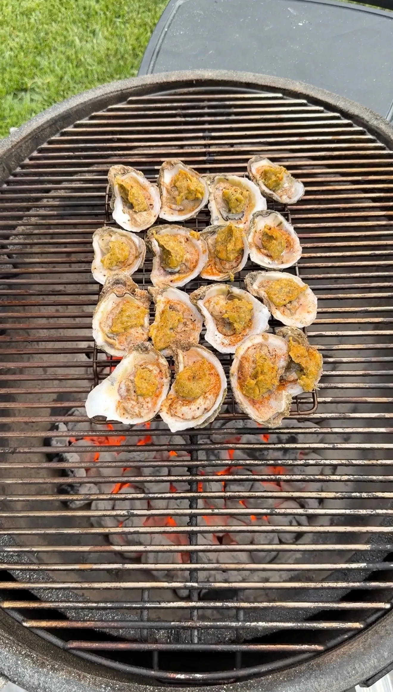 Garlic herb parmesan oysters in their half shells cooking on a barbecue grill grate
