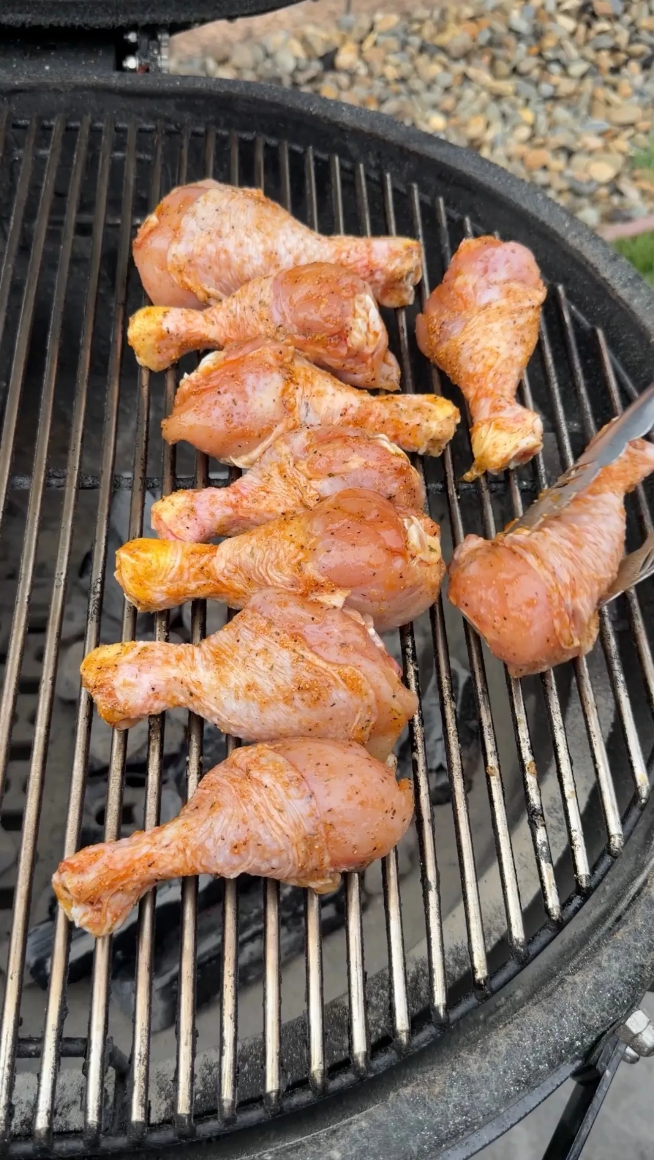 Seasoned chicken drumsticks cooking on a round barbecue grill with char marks and golden-brown crispy skin