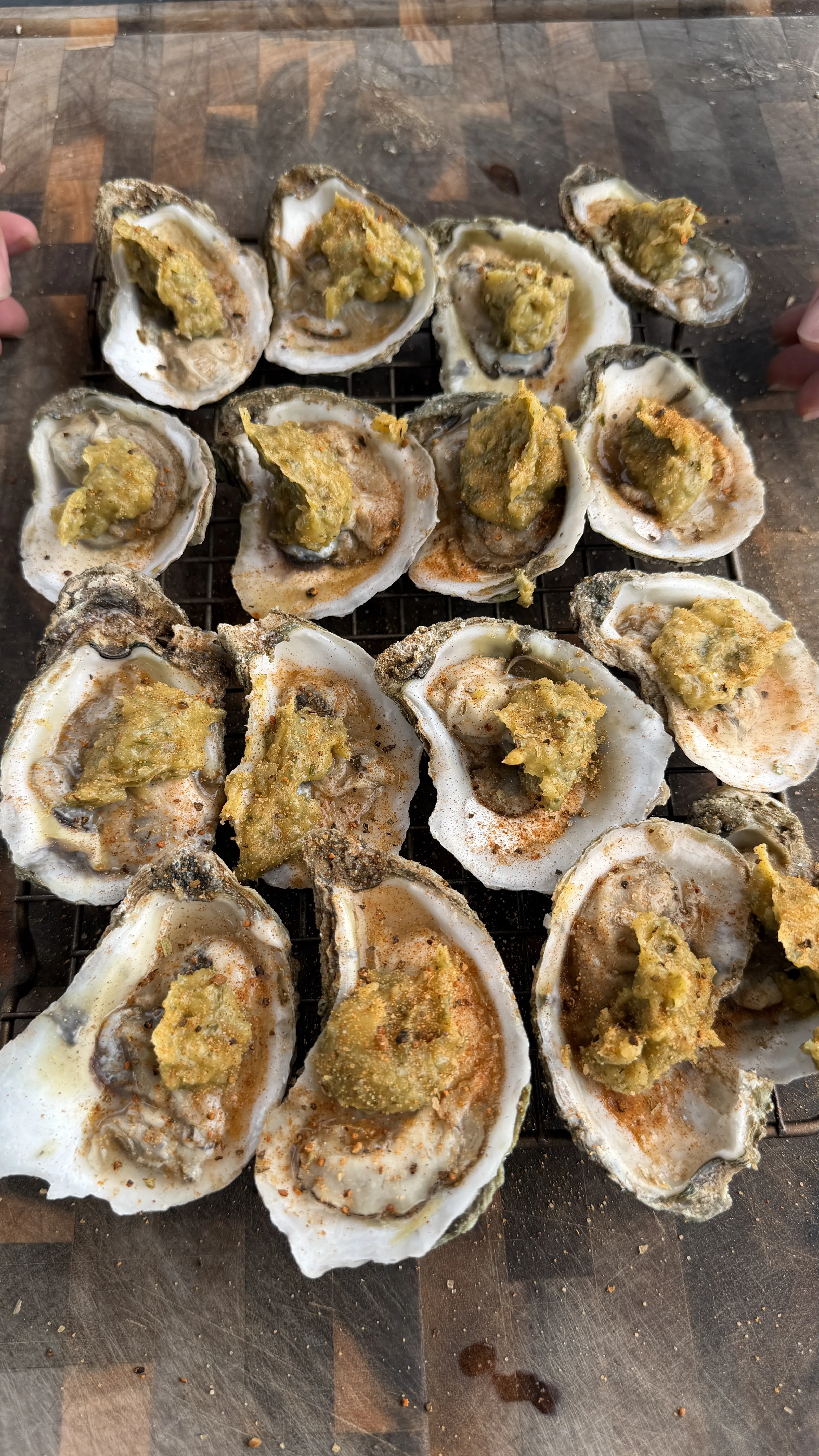 Finished grilled garlic herb parmesan oysters with charred lemon wedges on grill grate