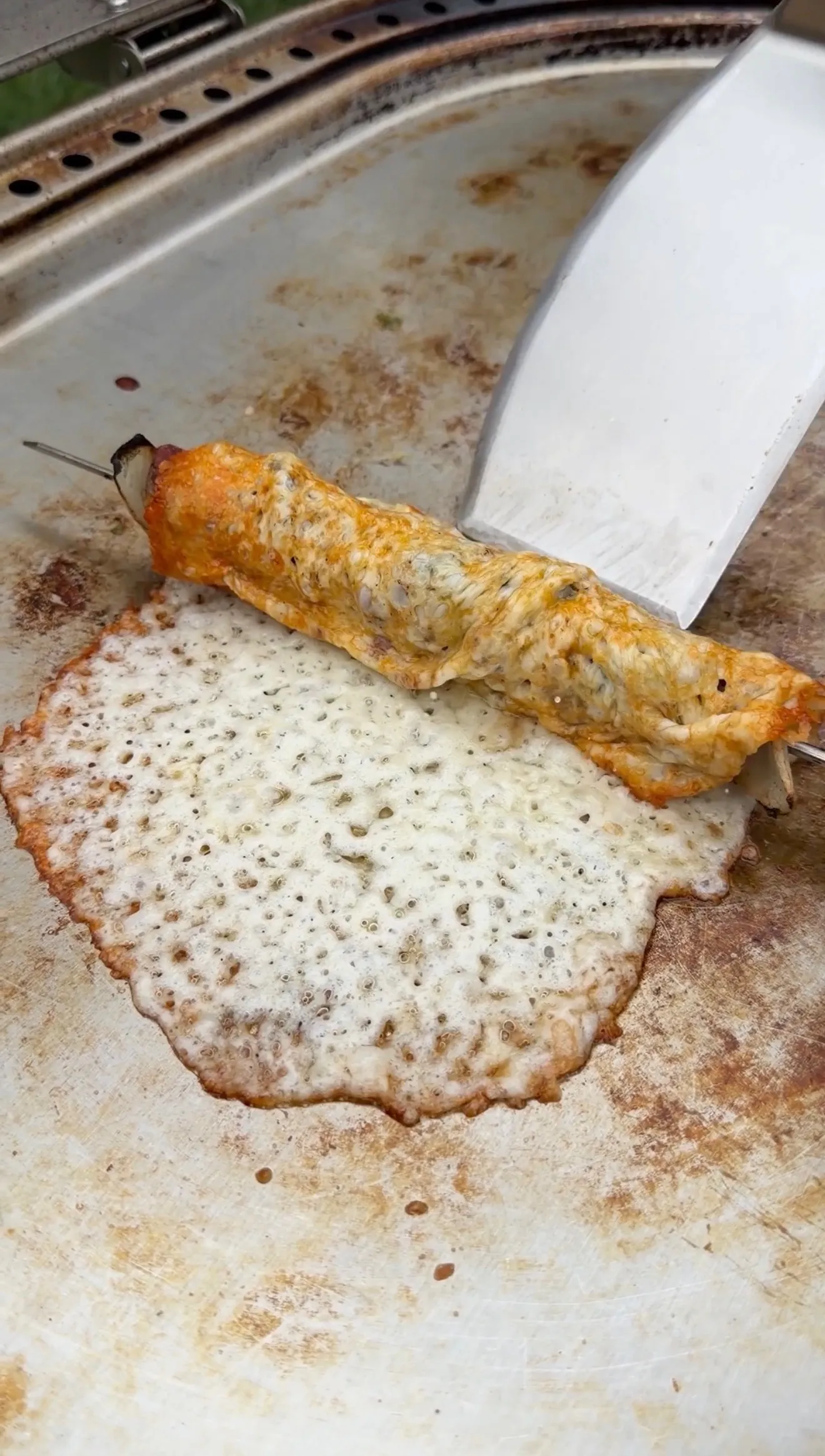 Grilled steak kebab with golden melted cheese crust on cooking surface showing chimichurri seasoning