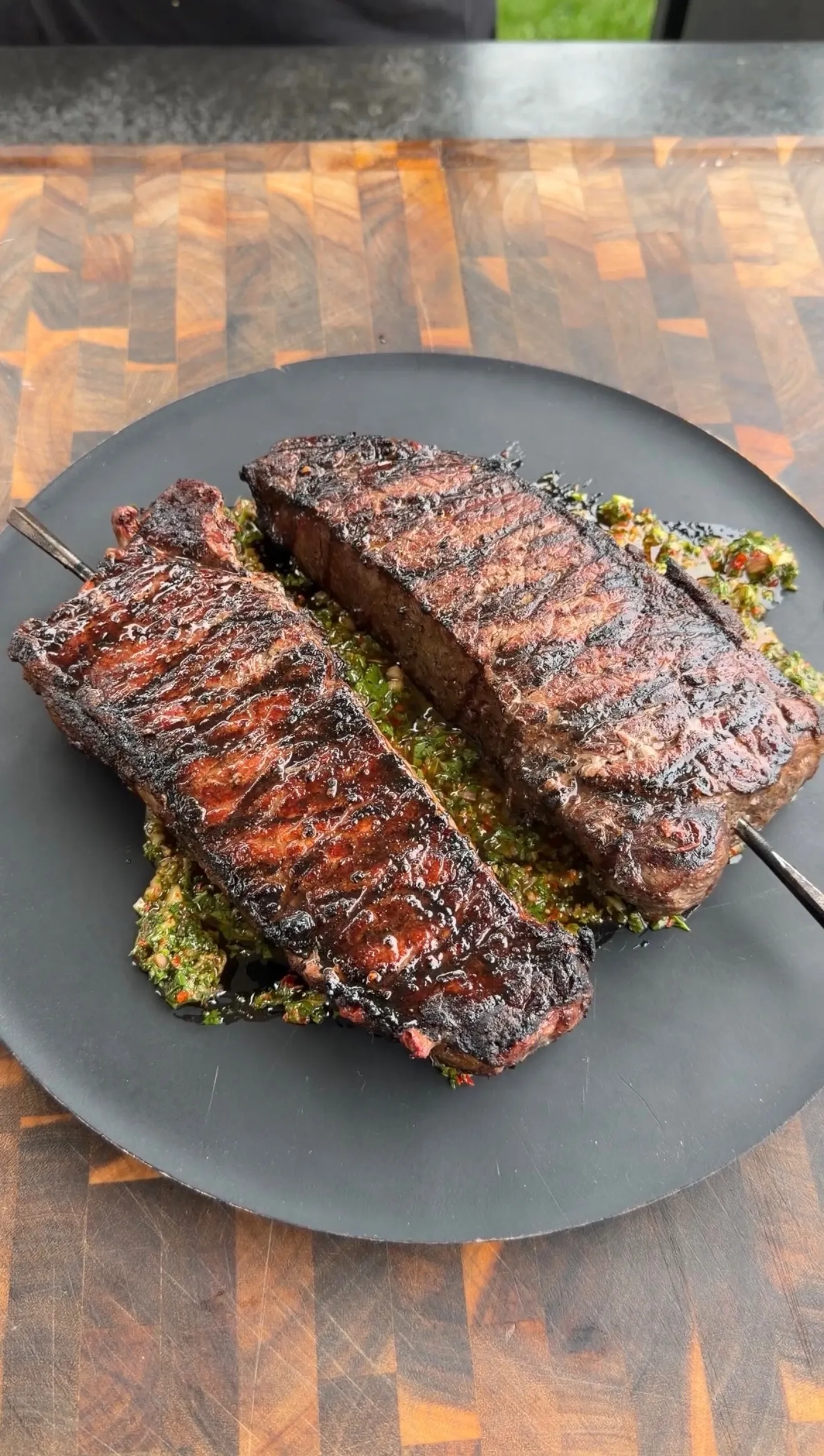 Grilled strip steaks resting on green board sauce
