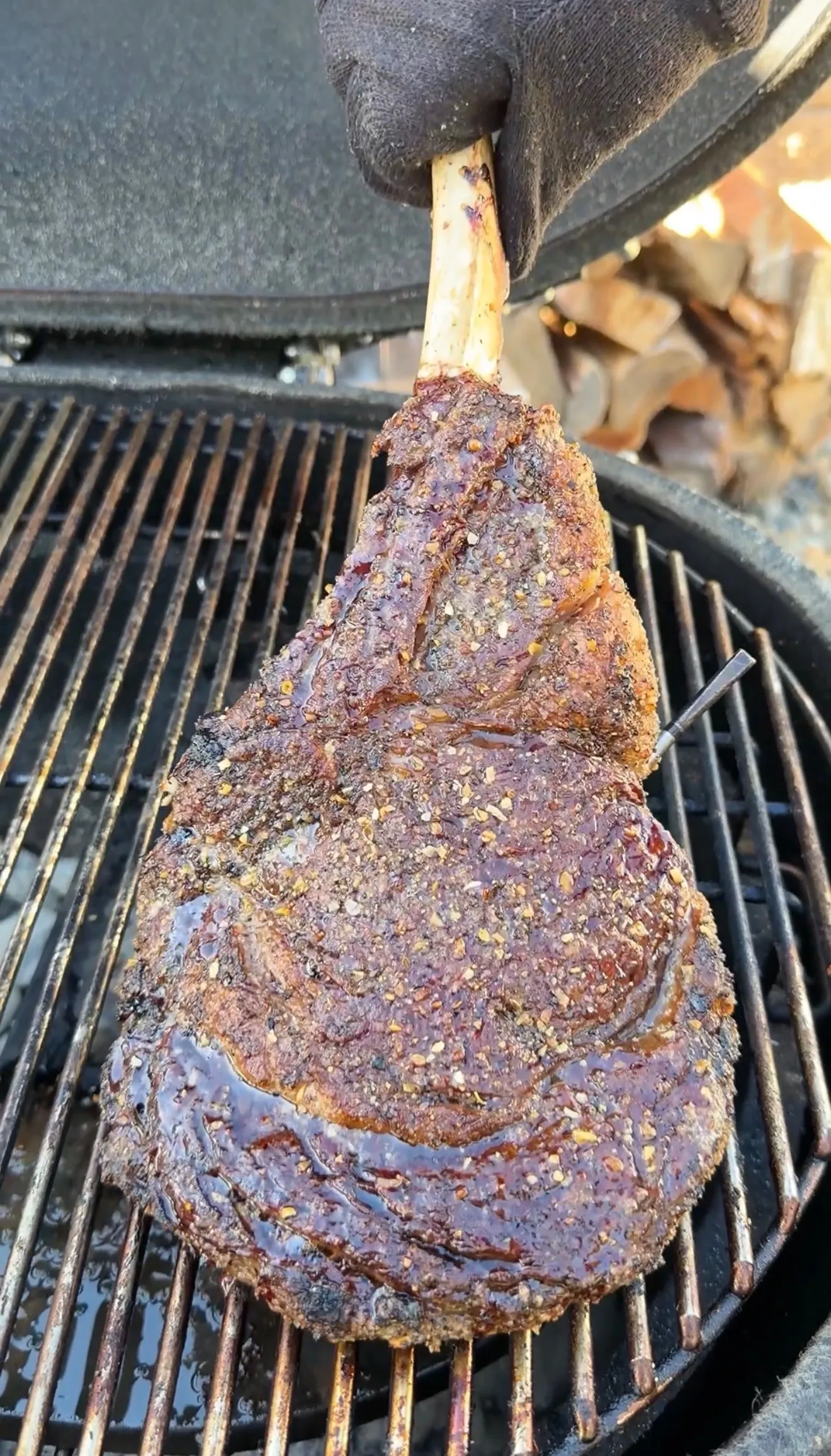Seasoned tomahawk steak with herb crust being grilled on outdoor barbecue grates