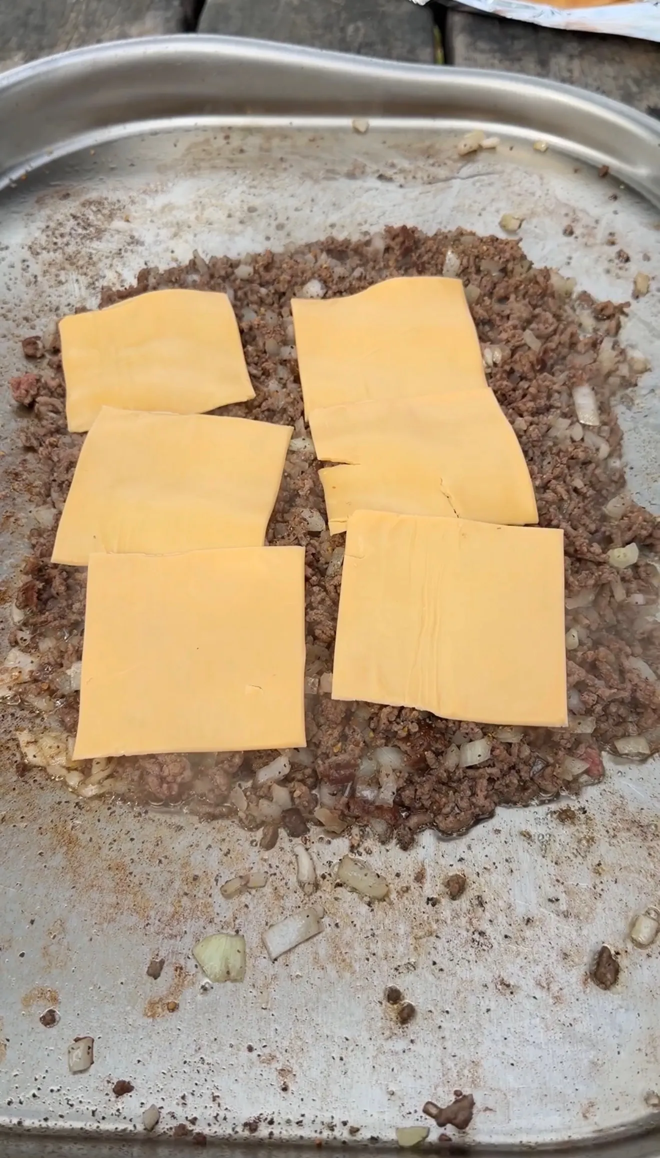 Ground beef with American cheese slices melting in cooking pan