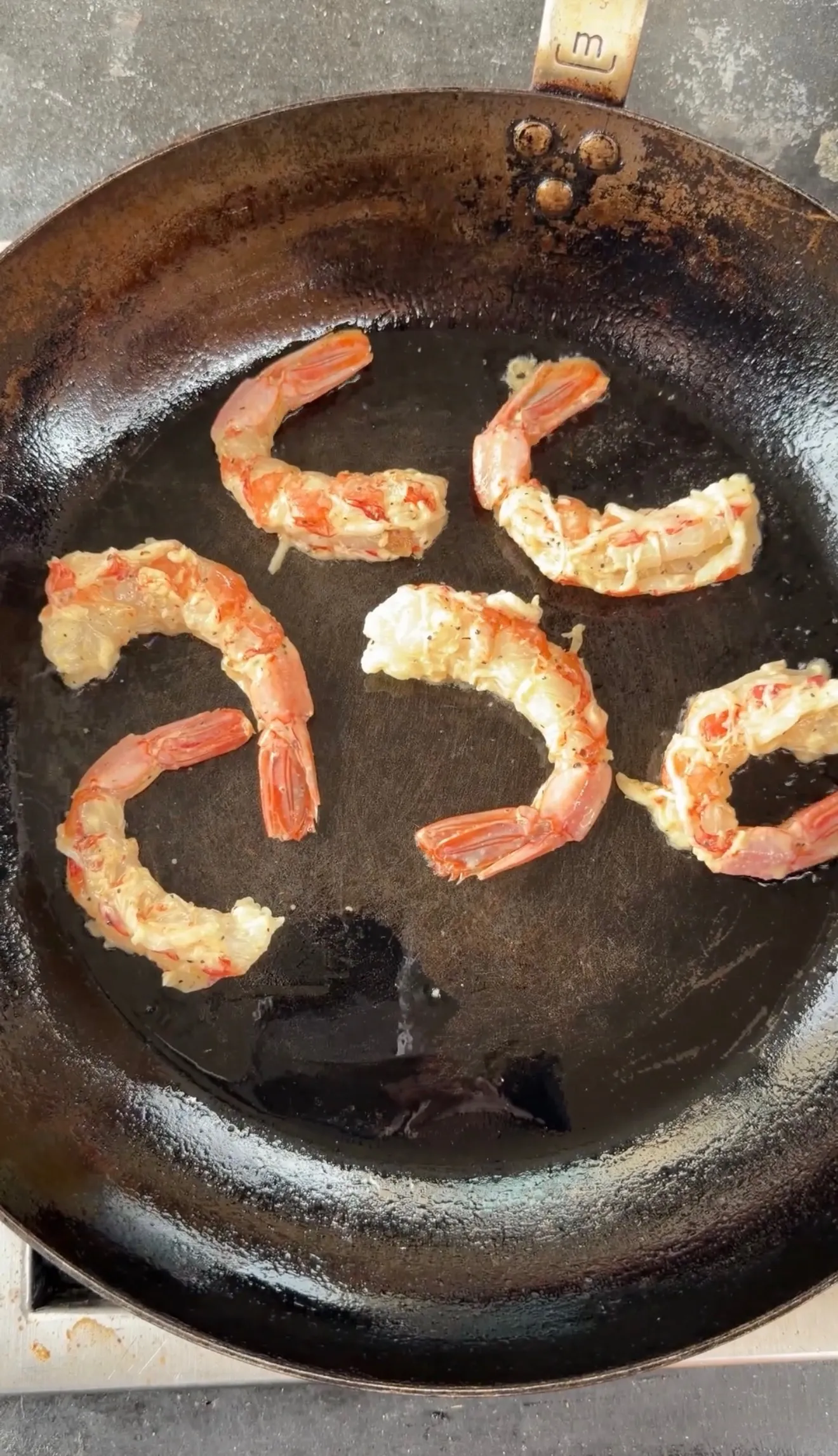Lemon pepper shrimp sizzling in a black cast iron skillet showing pink and white cooked shrimp