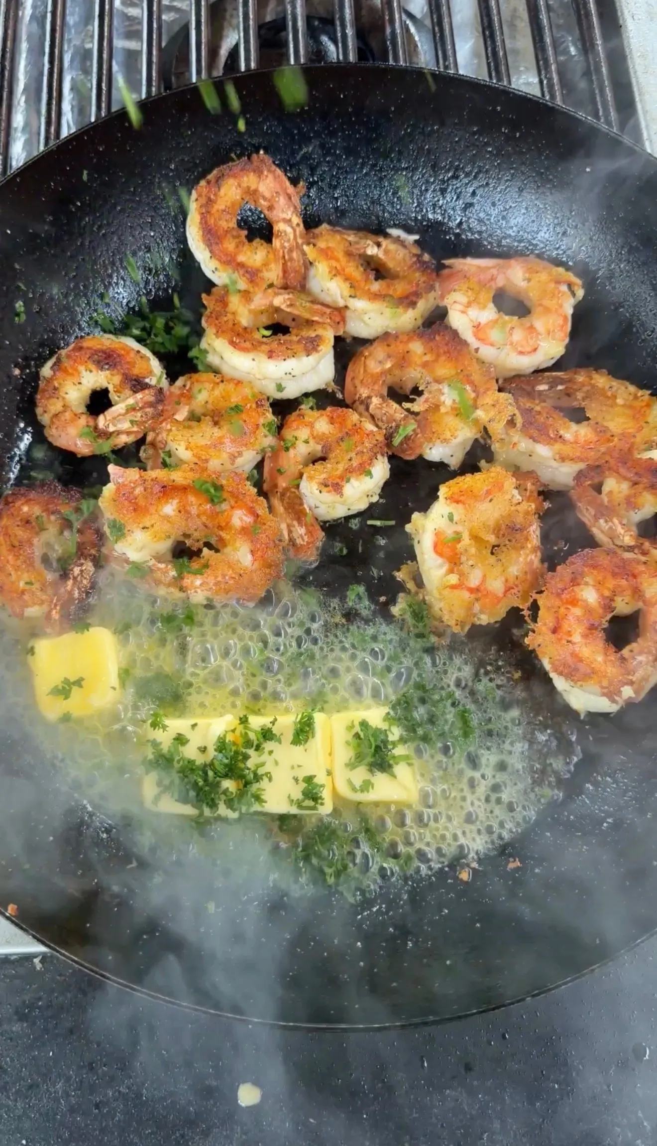 Golden lemon pepper crispy shrimp sizzling in a black pan with melted butter and fresh herbs