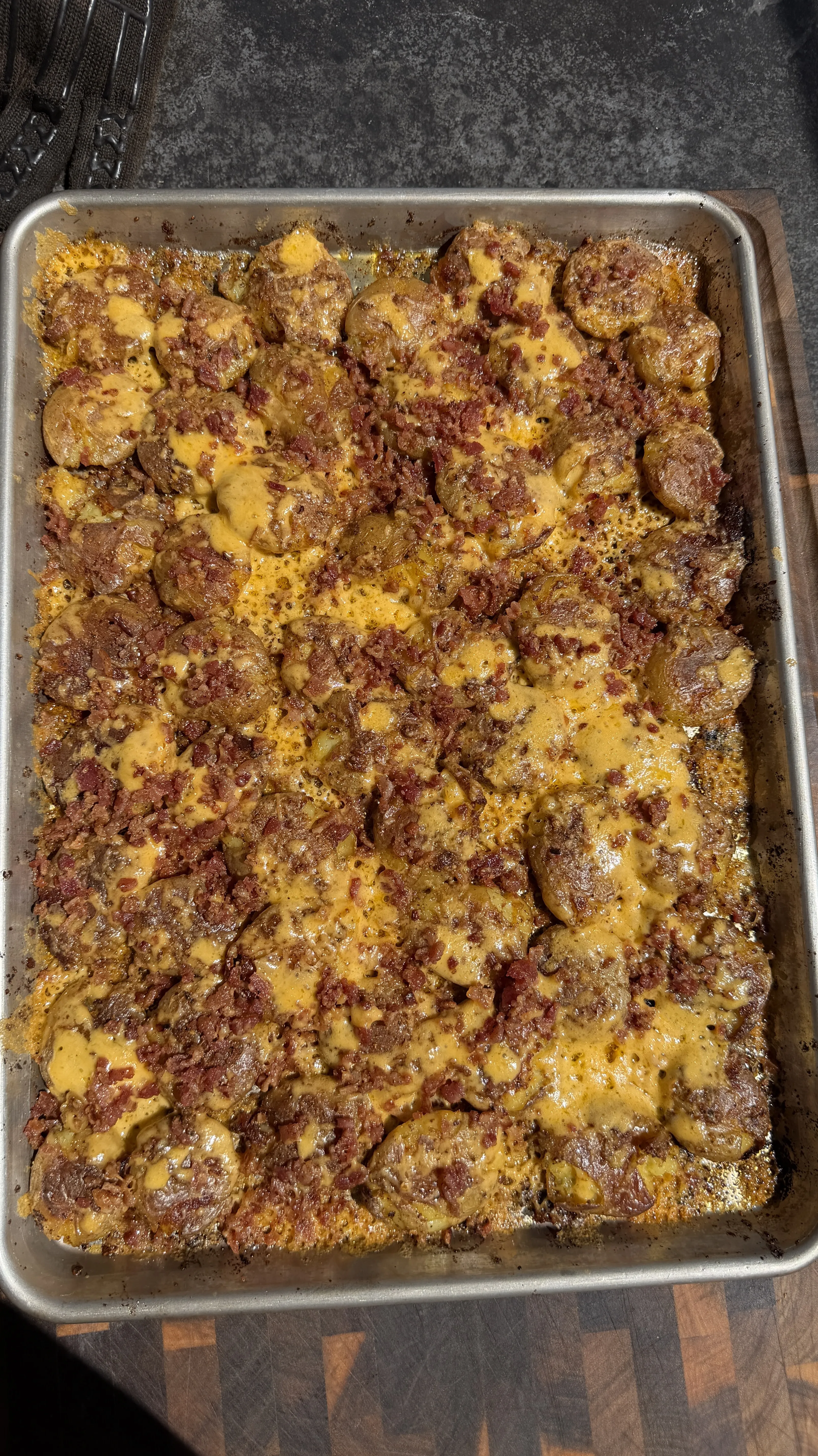 Loaded smashed mini potatoes with bacon and cheese on baking sheet