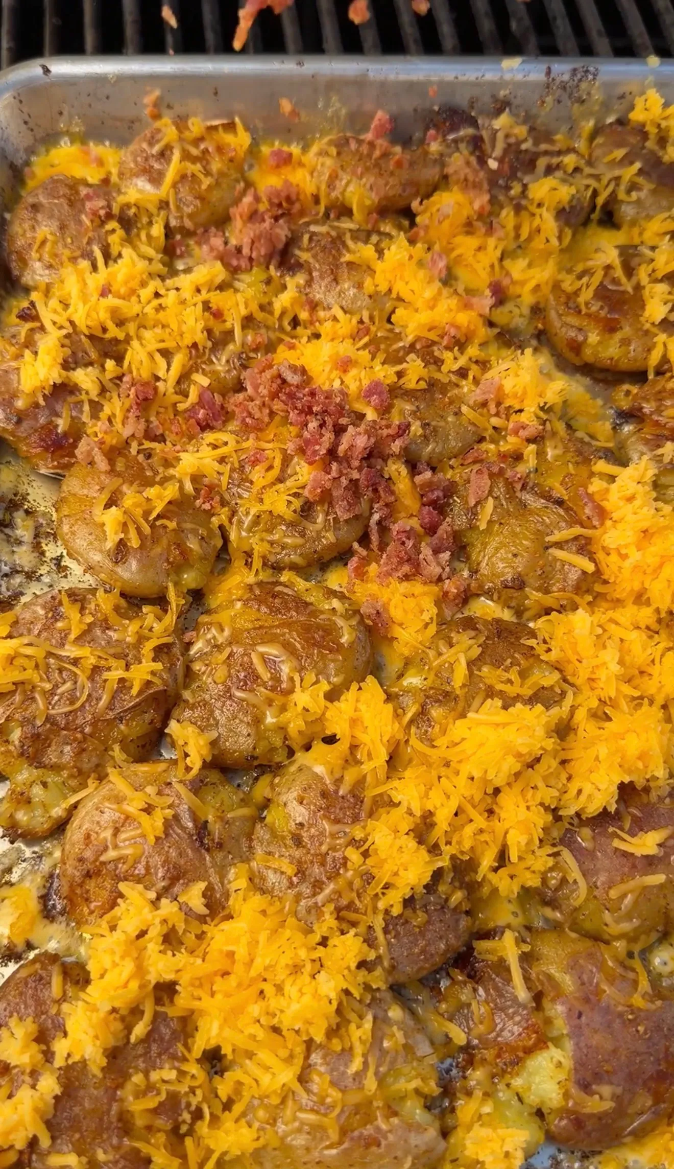 Smashed loaded mini potatoes topped with melted cheddar cheese and crispy bacon bits in baking dish