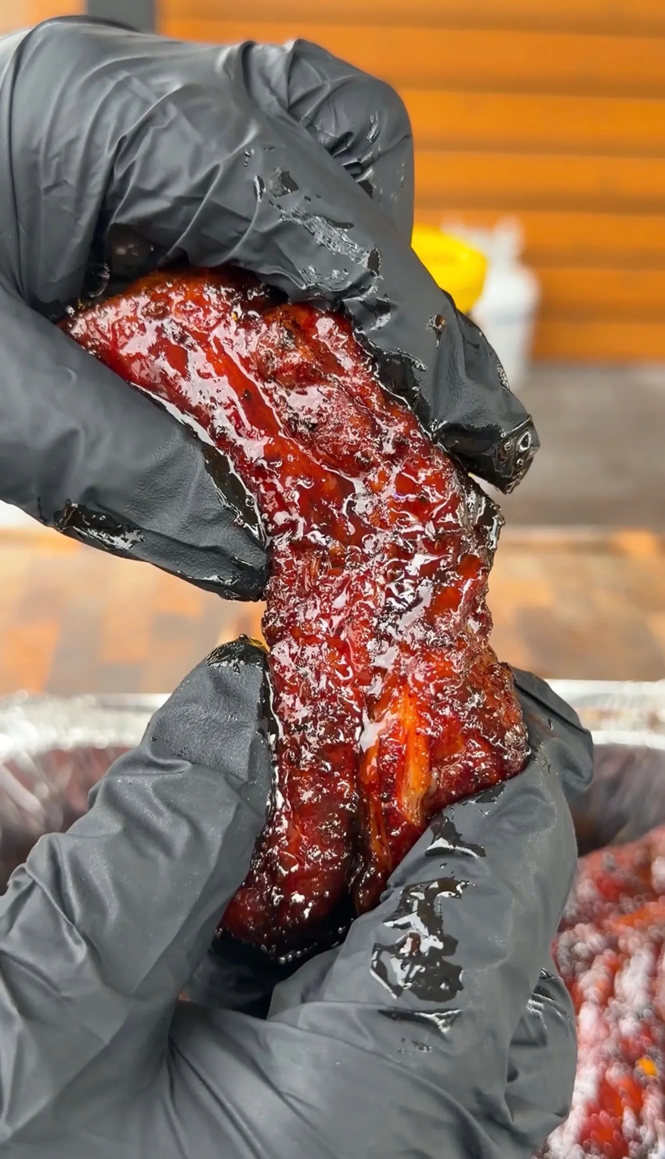 Sticky glazed molasses hot honey ribs being held up showing the glossy lacquered finish
