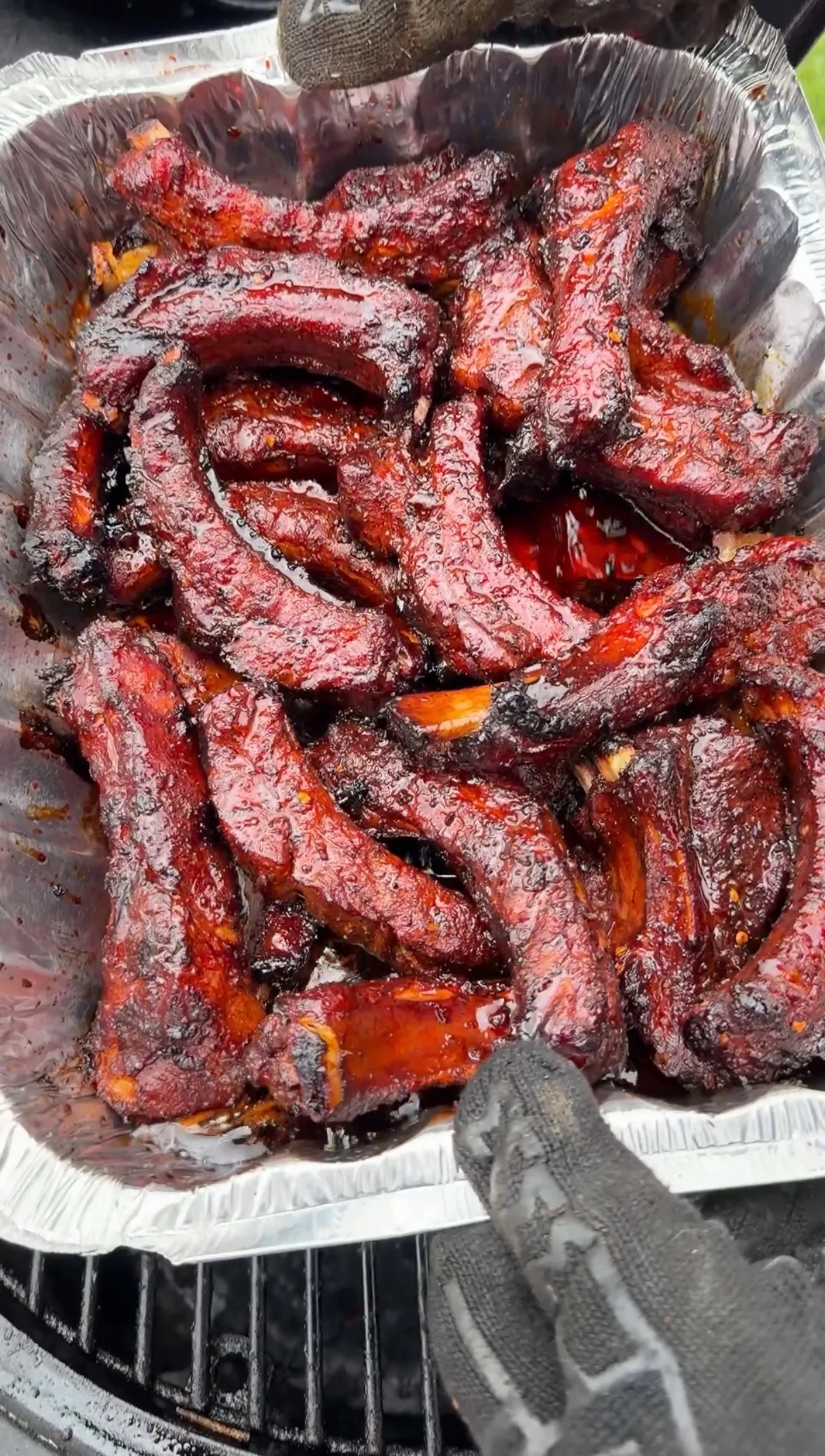 Uncovered molasses hot honey ribs glazed with sticky sauce in a foil pan after braising