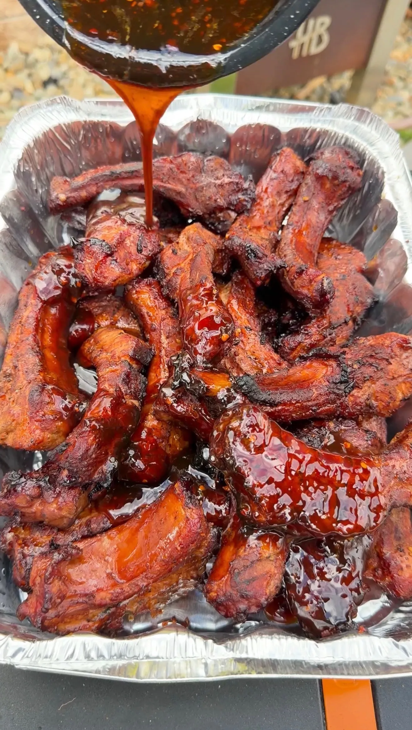Molasses hot honey ribs being drizzled with sticky glossy sauce as the glaze sets