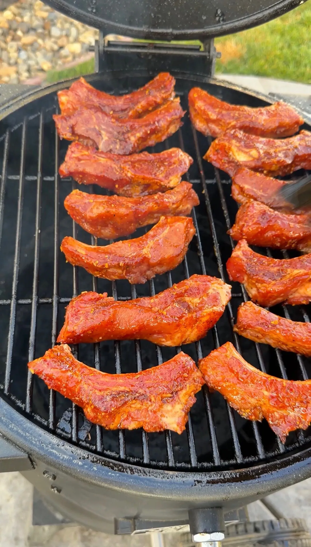 Seasoned molasses hot honey ribs smoking on a barbecue smoker with visible smoke ring forming