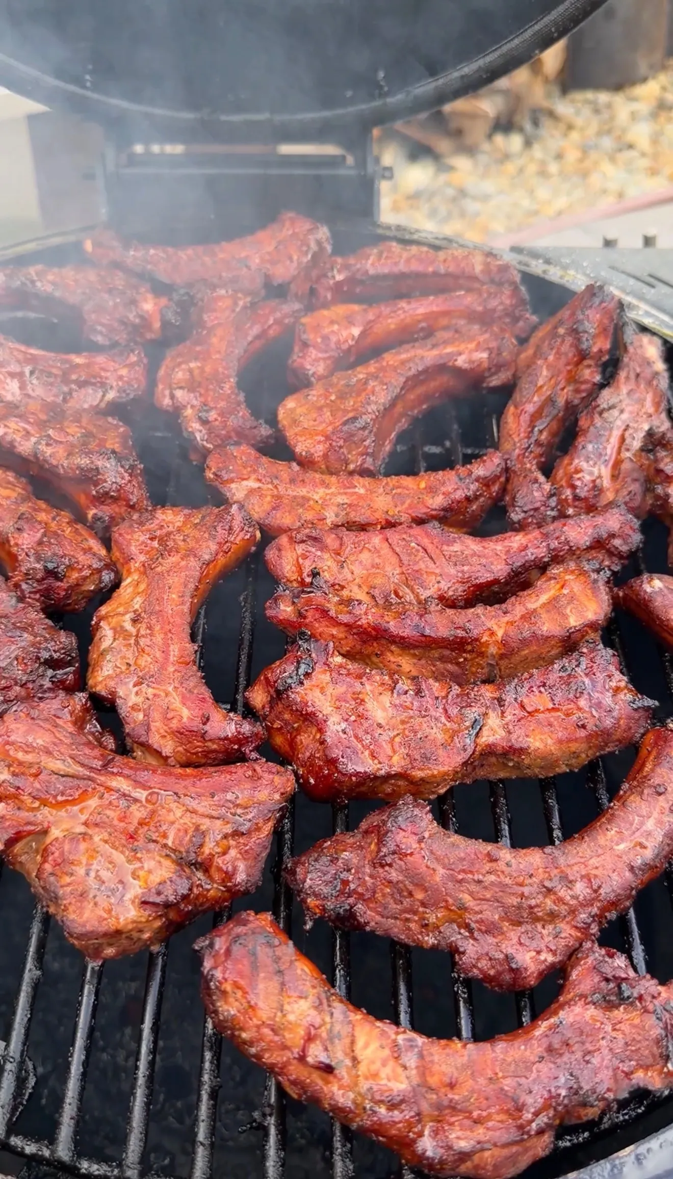 Molasses hot honey ribs smoking on barbecue grates with dark bark forming
