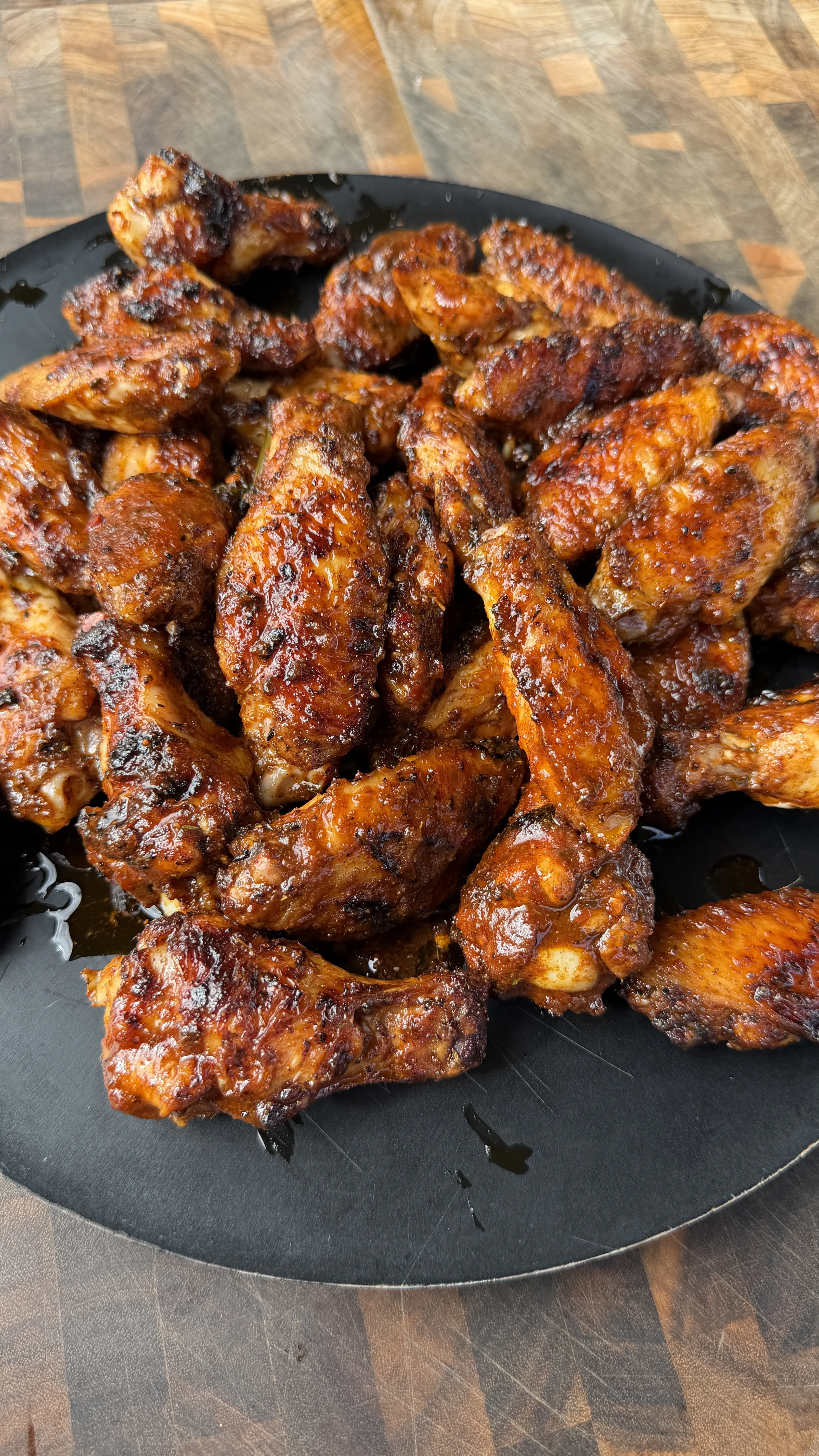 Crispy Nashville hot pickle brined chicken wings with caramelized glaze served on black cast iron plate