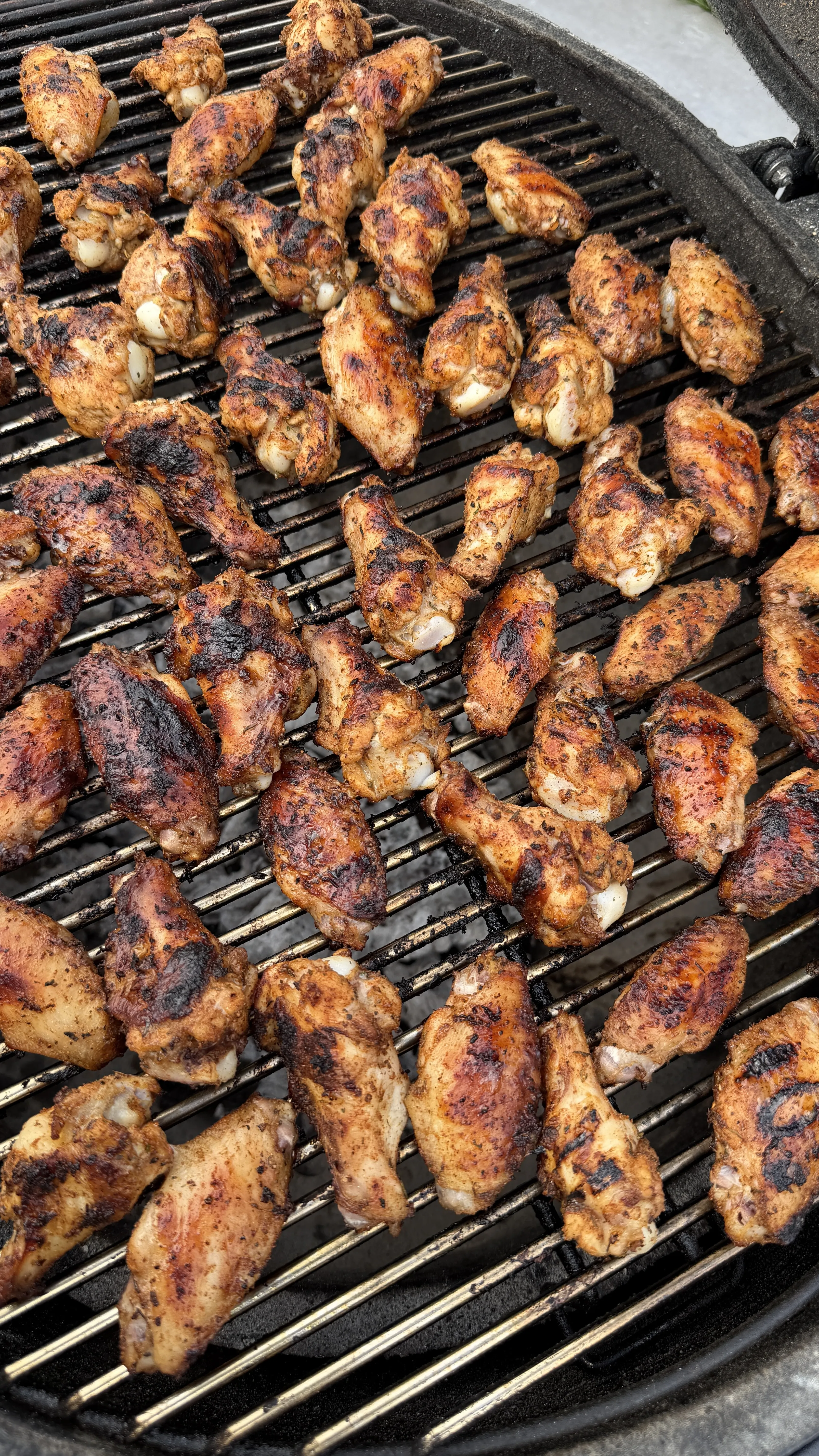 Nashville hot pickle brined chicken wings with golden-brown char marks cooking on a round BBQ grill