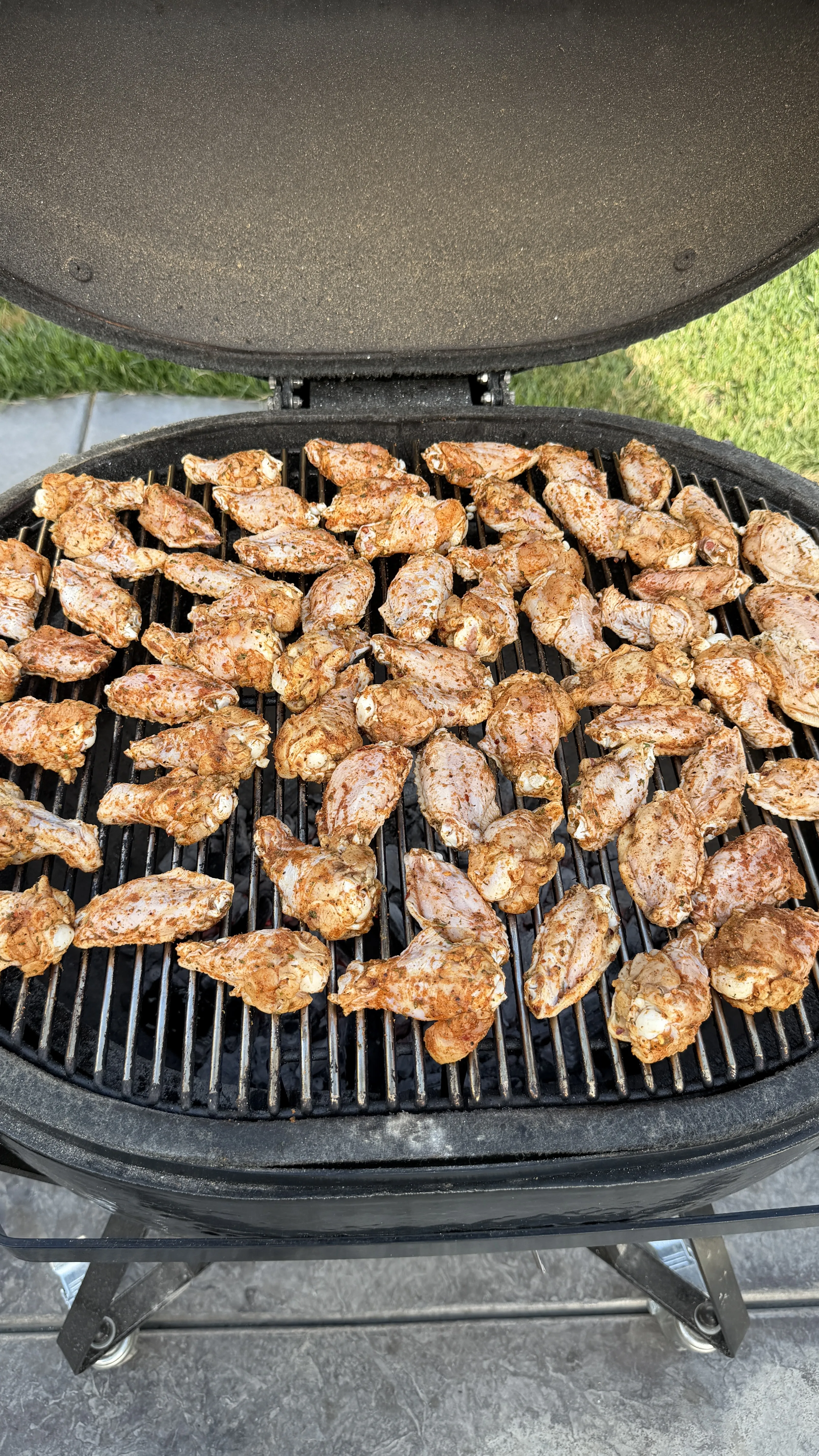 Nashville hot pickle brined chicken wings cooking on a round charcoal grill with seasoned golden-brown coating