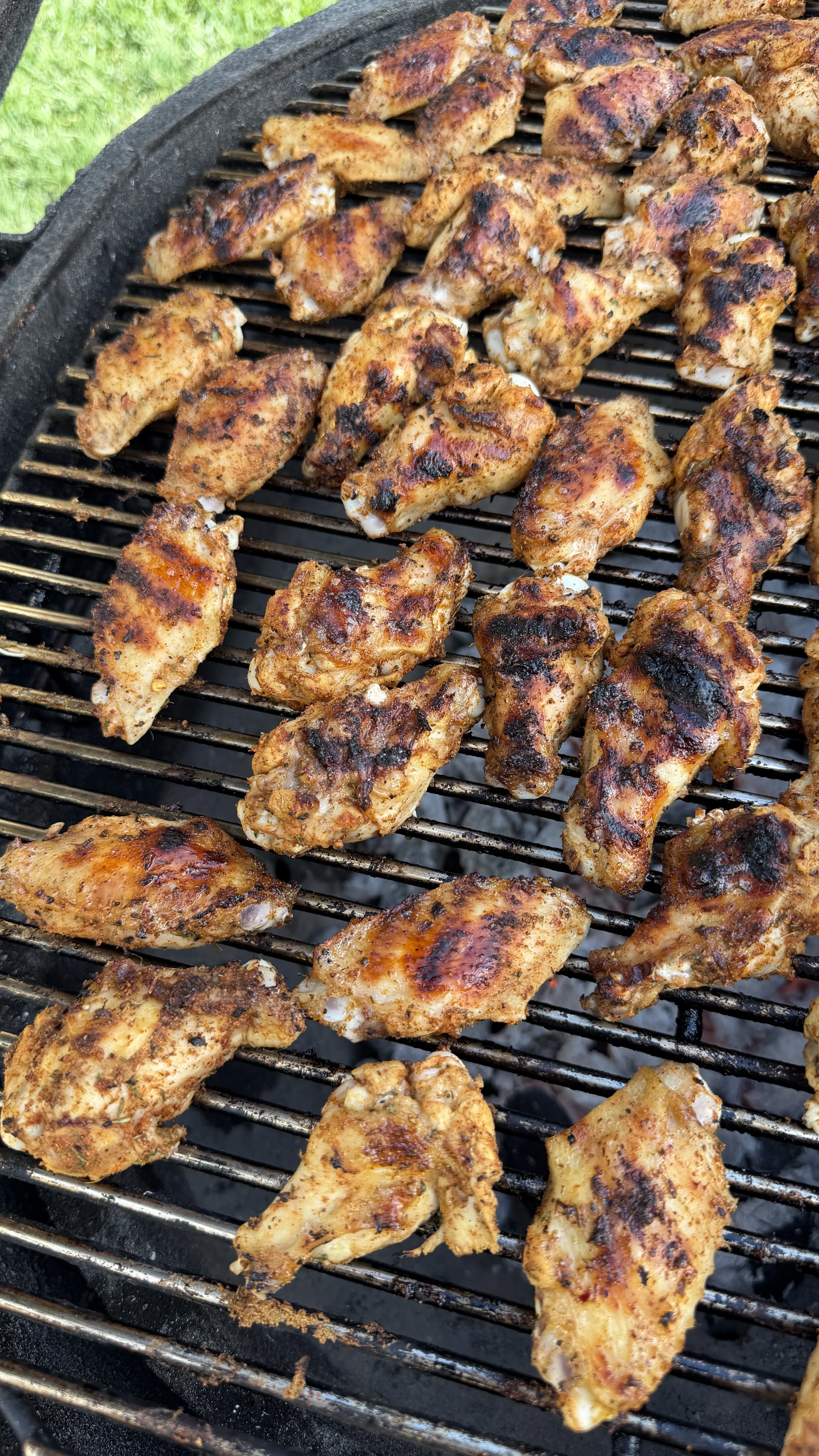 Nashville hot pickle brined chicken wings cooking on black grill grates with golden brown char marks