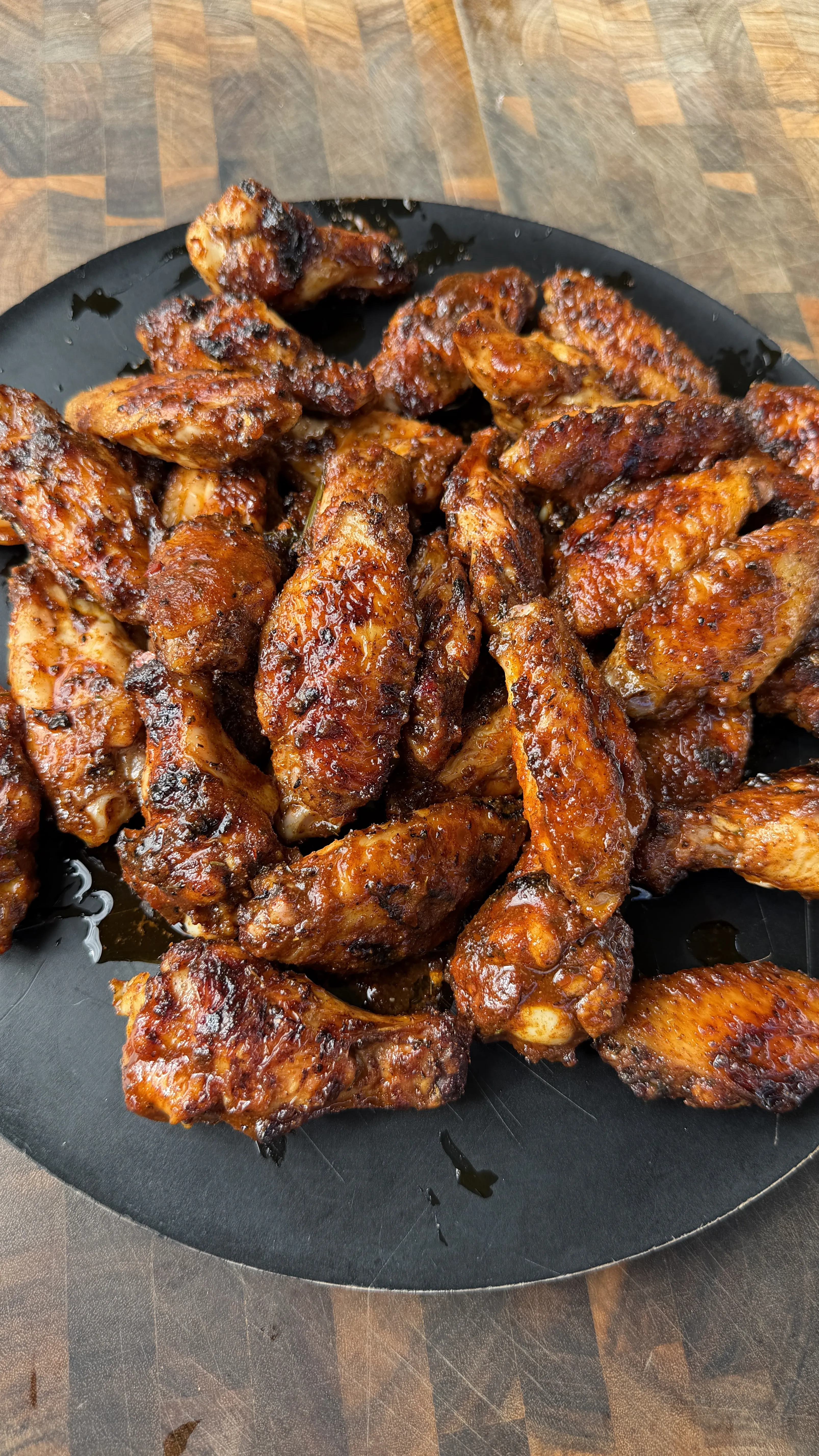 Nashville hot pickle brined chicken wings with crispy golden-brown skin and caramelized glaze on a slate plate