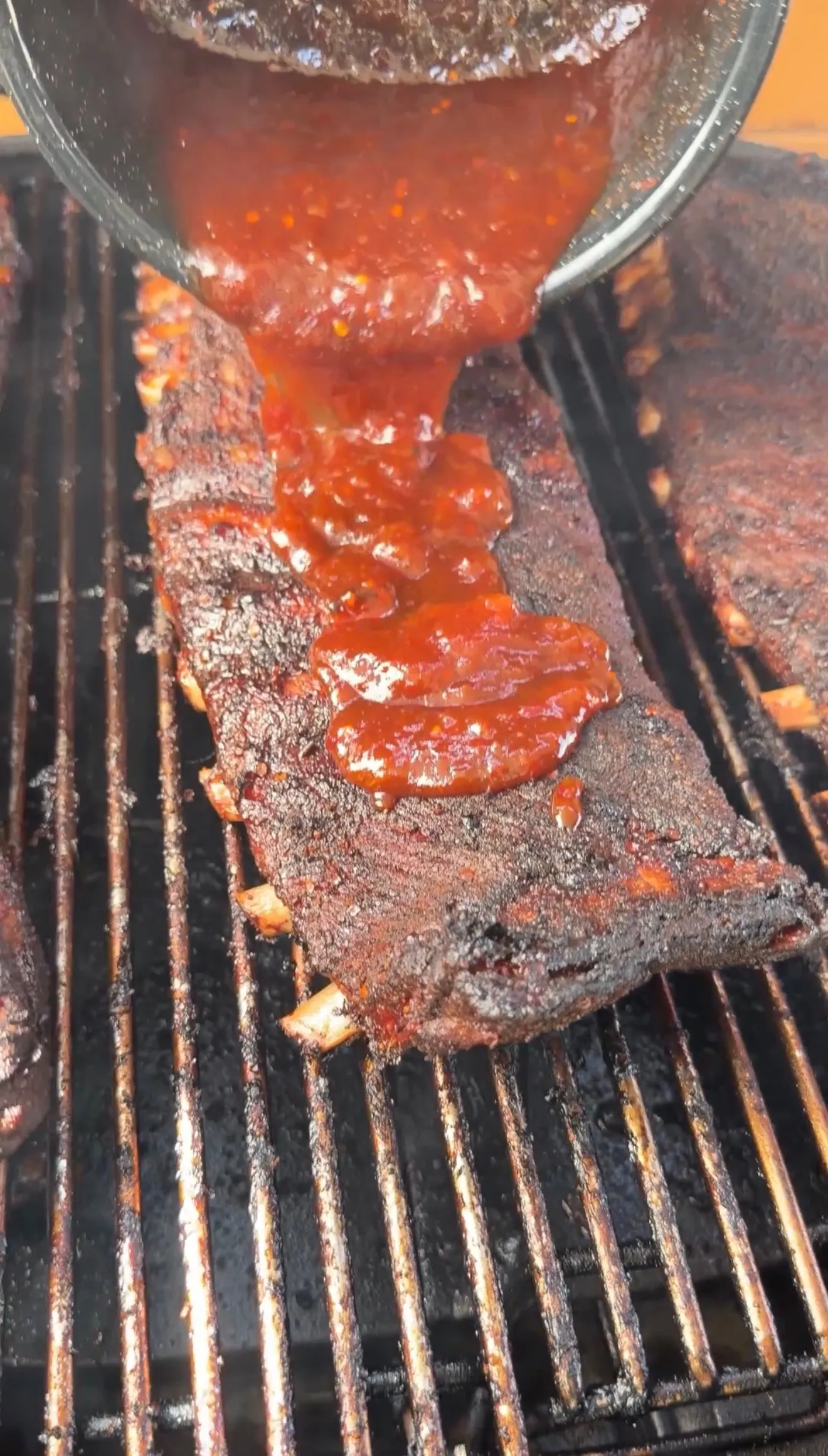 Peach bourbon glaze being applied to BBQ ribs