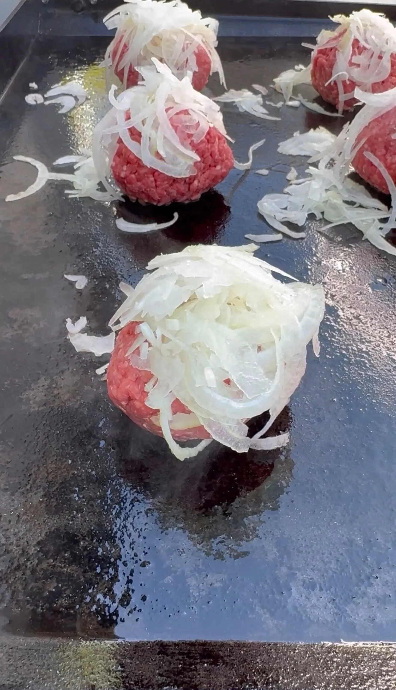 Raw ground beef patties on hot griddle