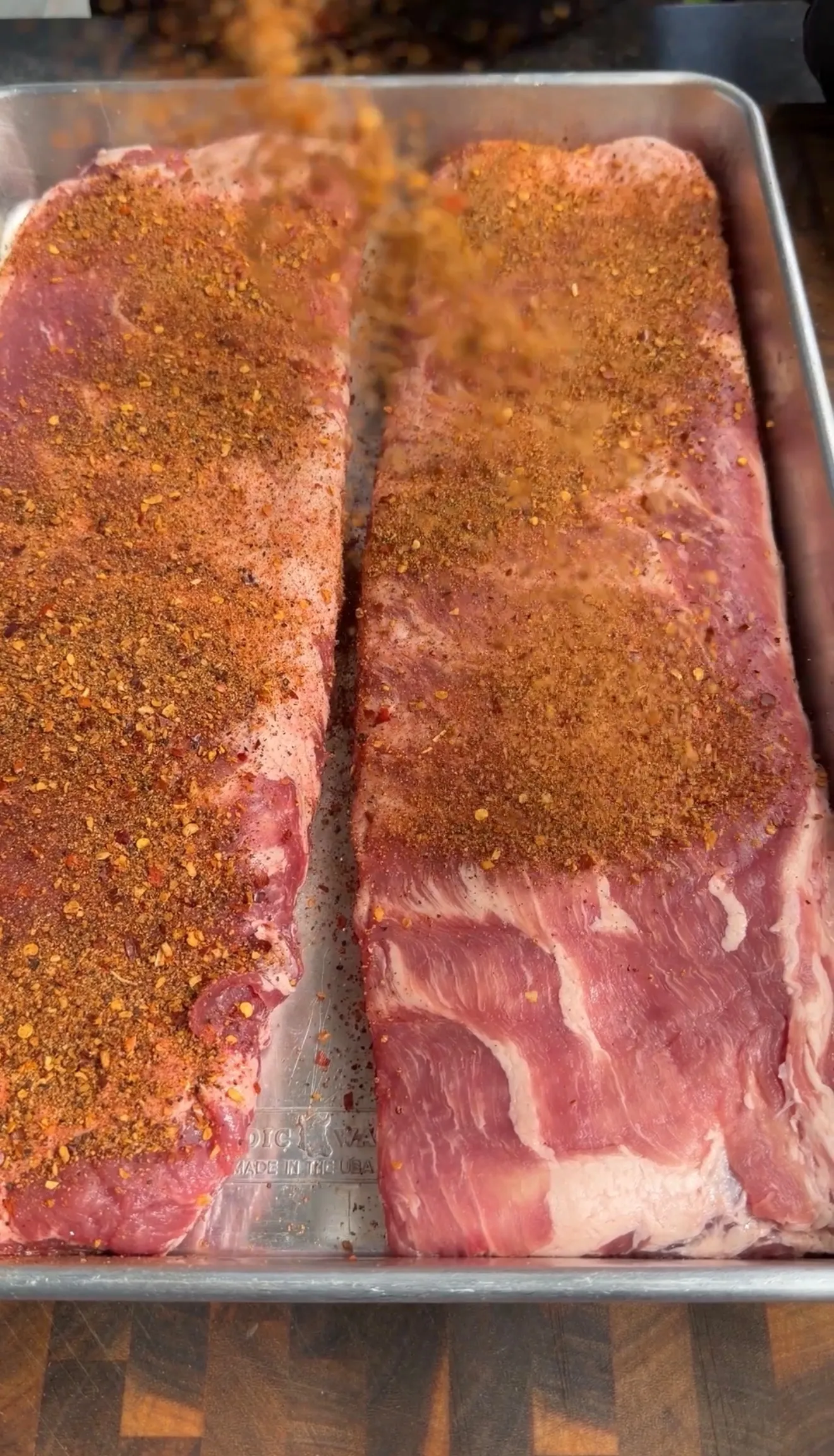 Raw pork ribs with dry rub seasoning in pan