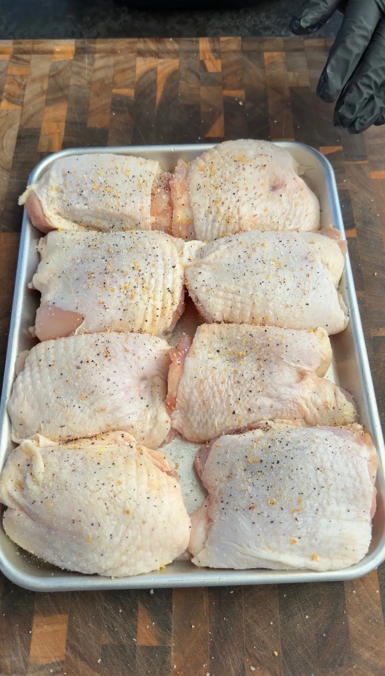 Raw seasoned chicken thighs in baking pan
