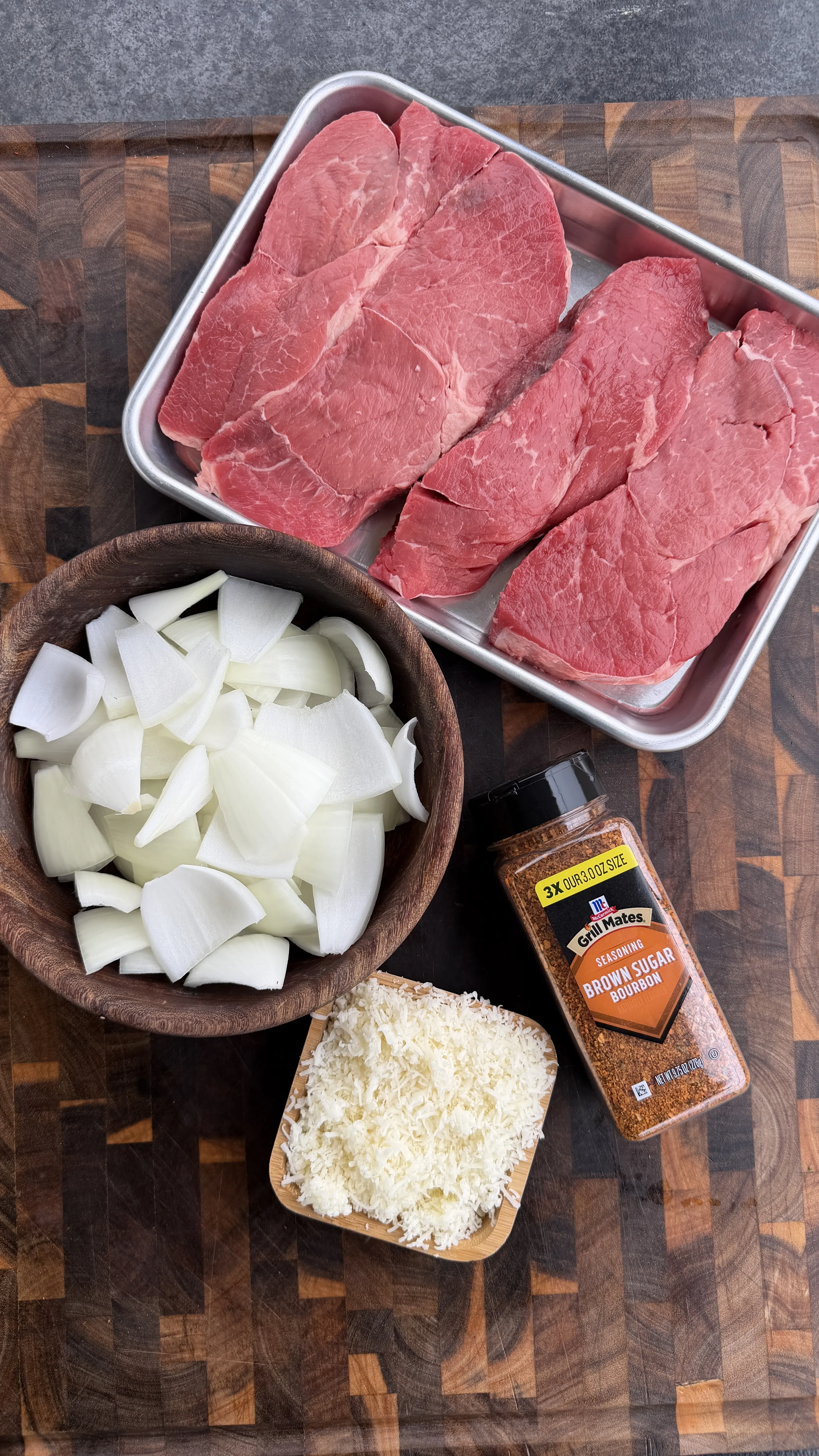 Raw beef steaks, sliced onions, shredded cheese and brown sugar bourbon seasoning prepared for chimichurri kebabs