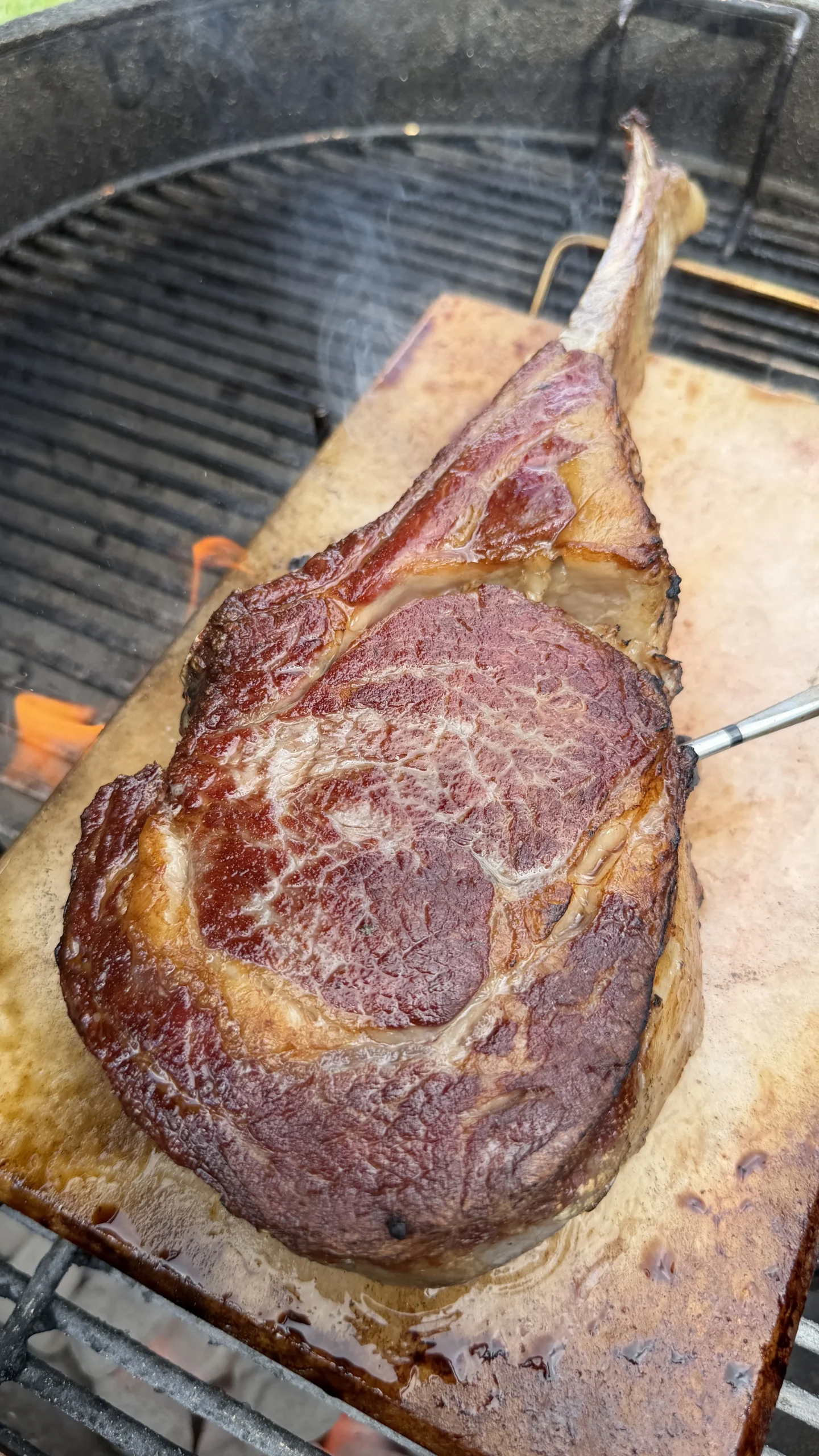 Perfectly seared tomahawk steak with beautiful marbling on a salt block over a charcoal grill