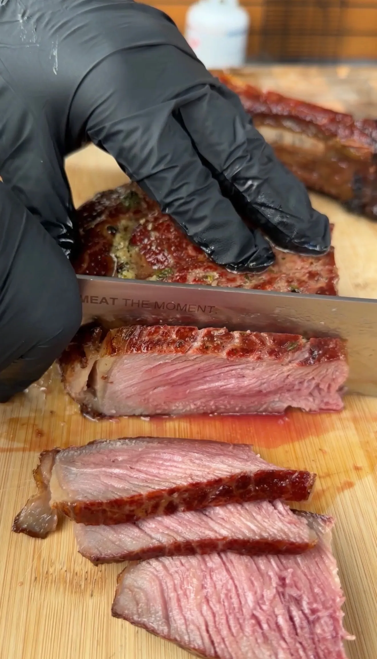 Salt block seared tomahawk steak being sliced on wooden cutting board, showing pink medium-rare interior