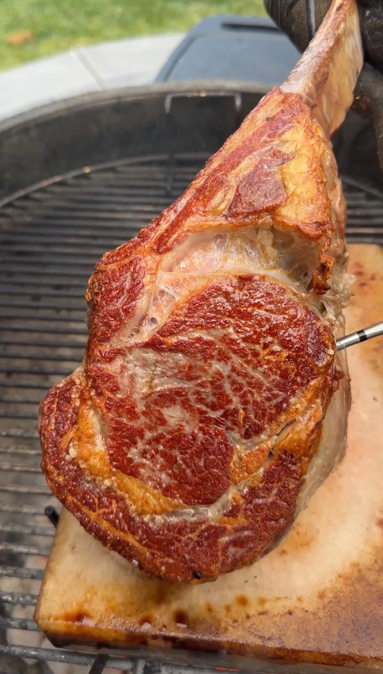 Perfectly seared tomahawk steak with golden-brown crust cooking on a salt block over grill grates