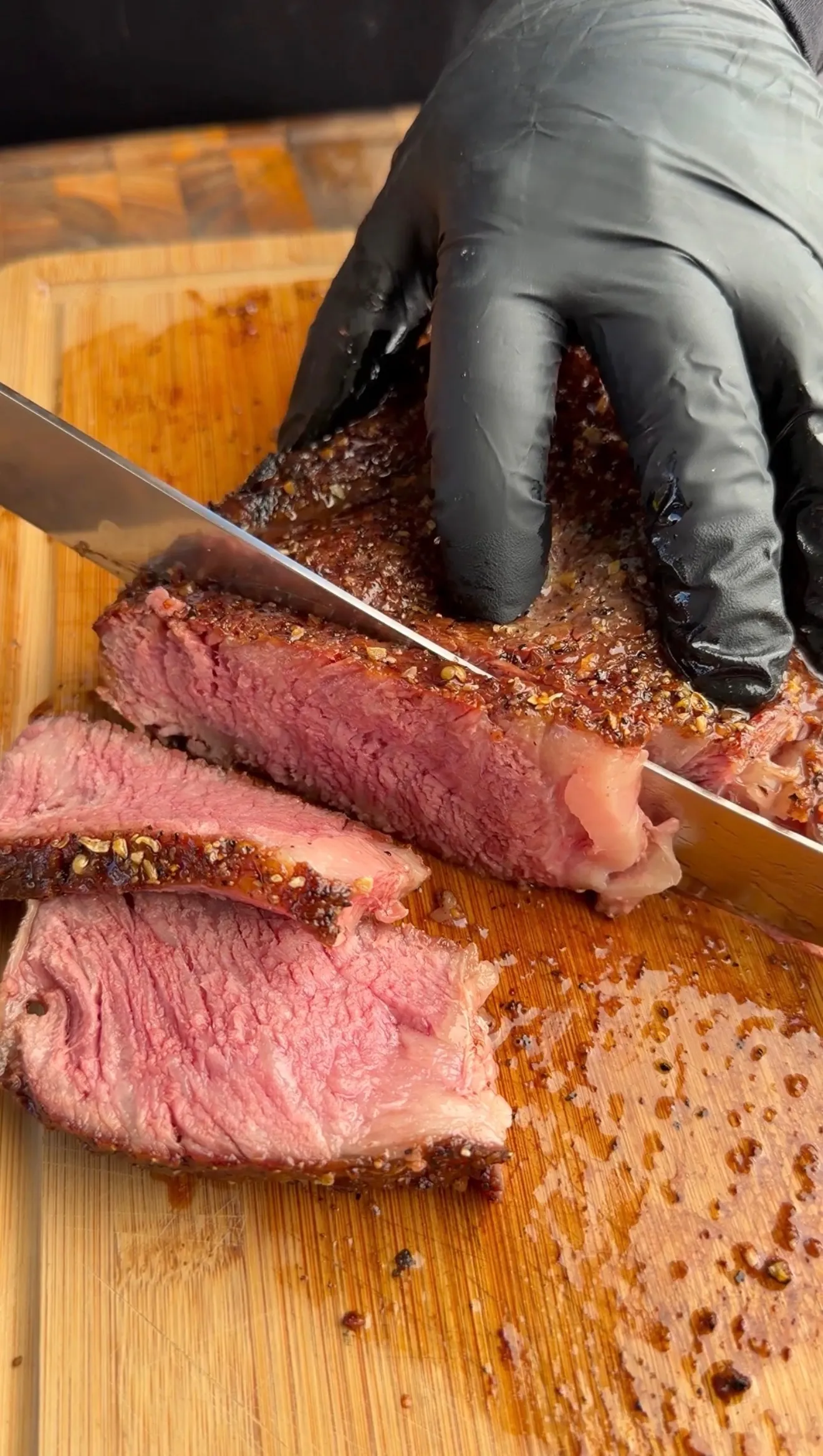 Perfectly grilled tomahawk steak being sliced on wooden cutting board showing medium-rare pink interior
