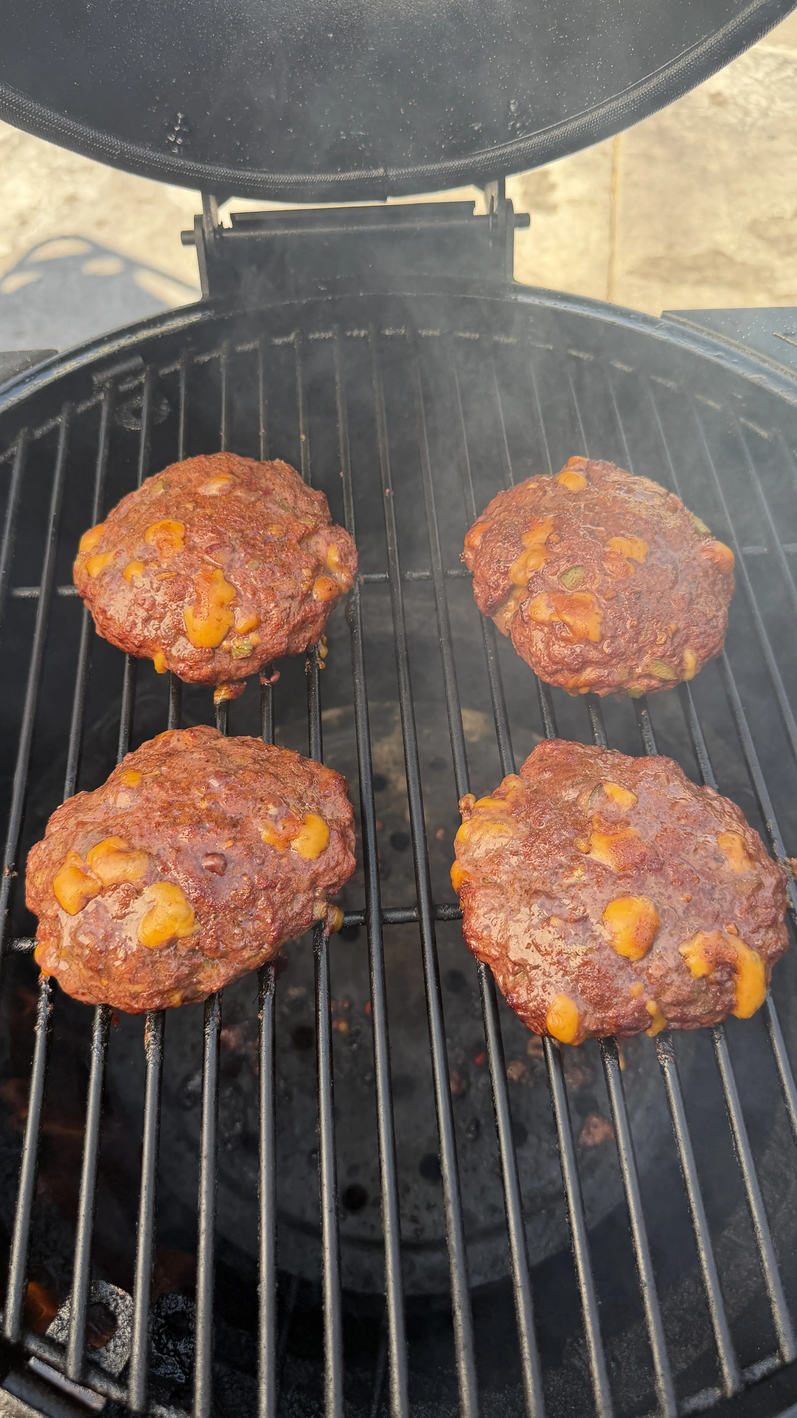 Smoked cheddar jalapeño burgers grilling on BBQ