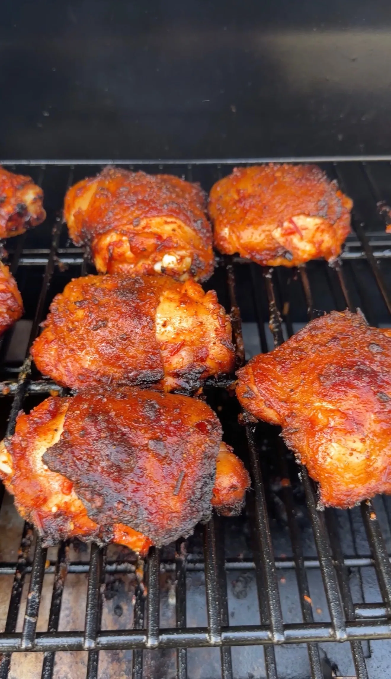 Smoked harissa chicken thighs grilling on grates