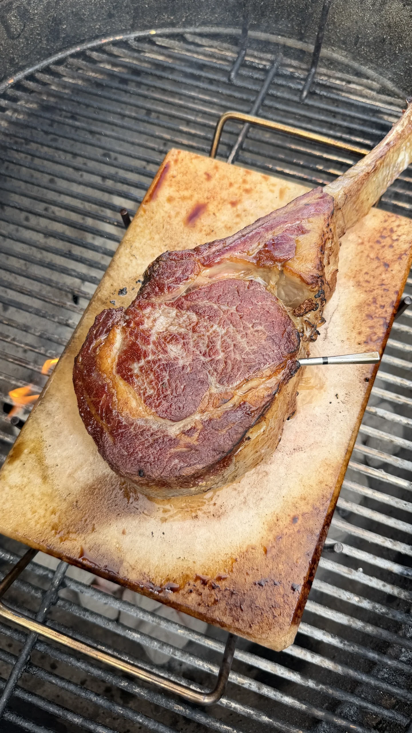 Tomahawk steak with long bone searing on a pink Himalayan salt block over grill grates