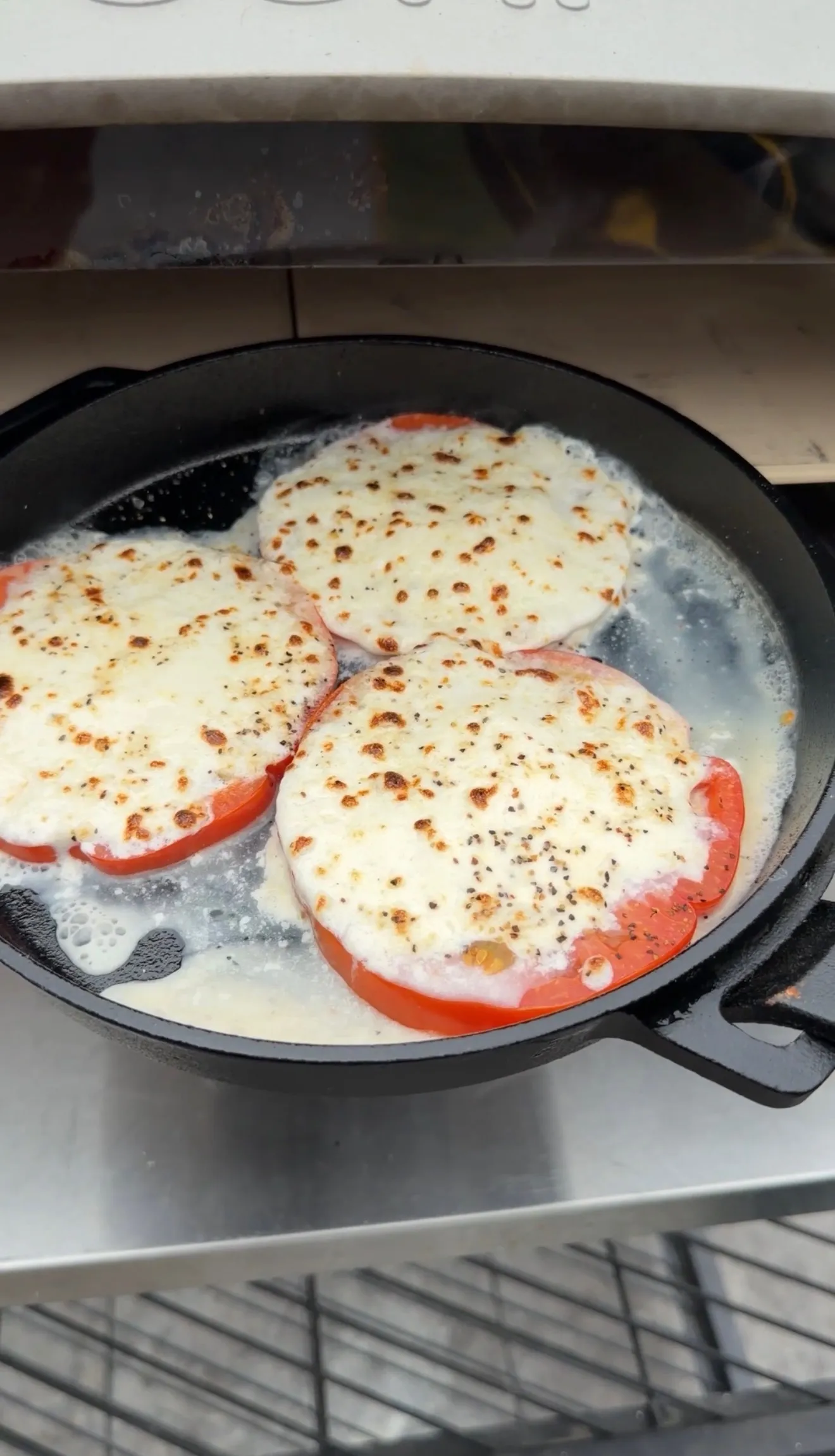 Tomato mozzarella rounds cooking in cast iron skillet