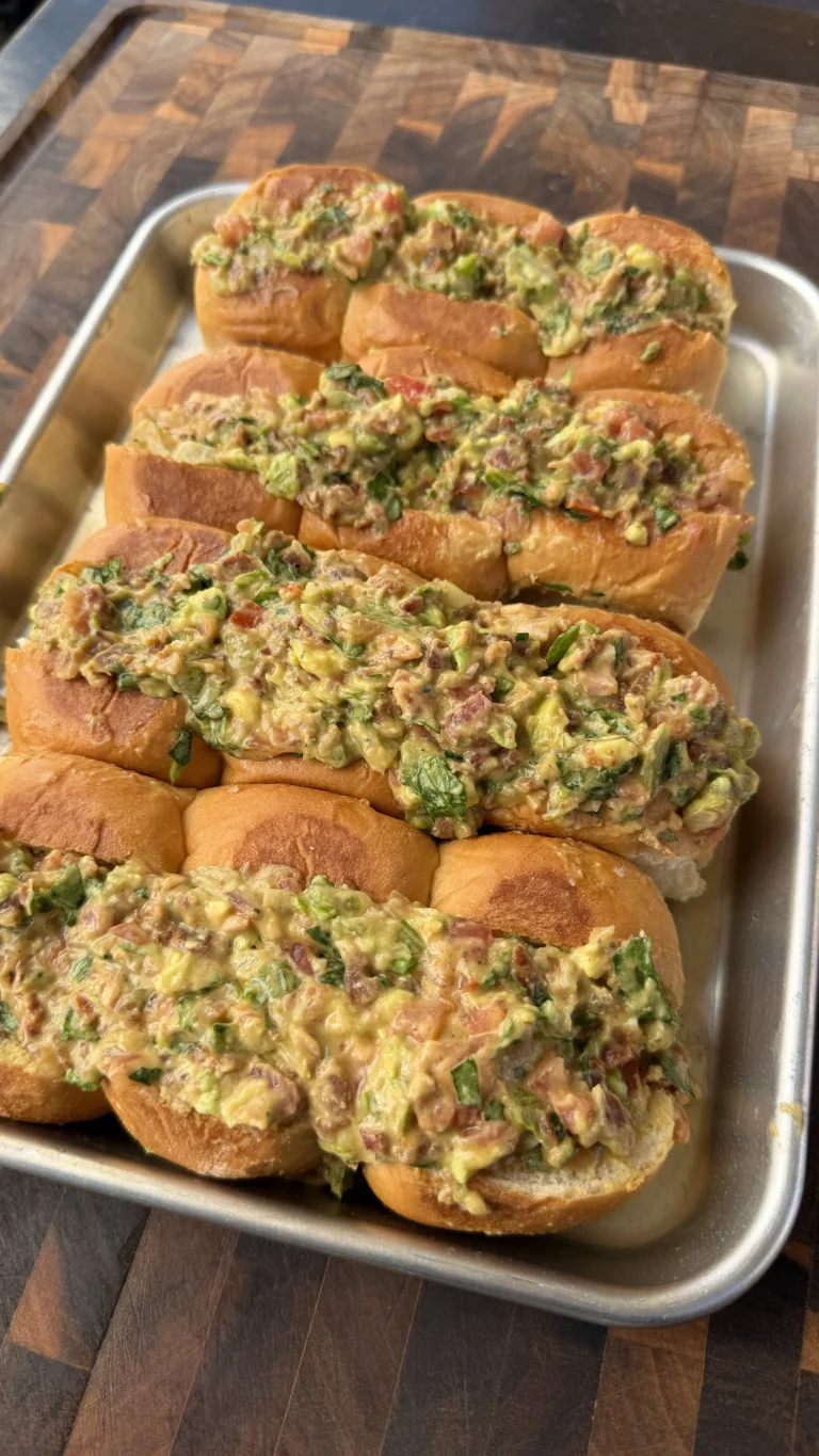 Avocado BLT chopped sliders topped with chunky guacamole, bacon, and herbs on toasted rolls in a metal tray