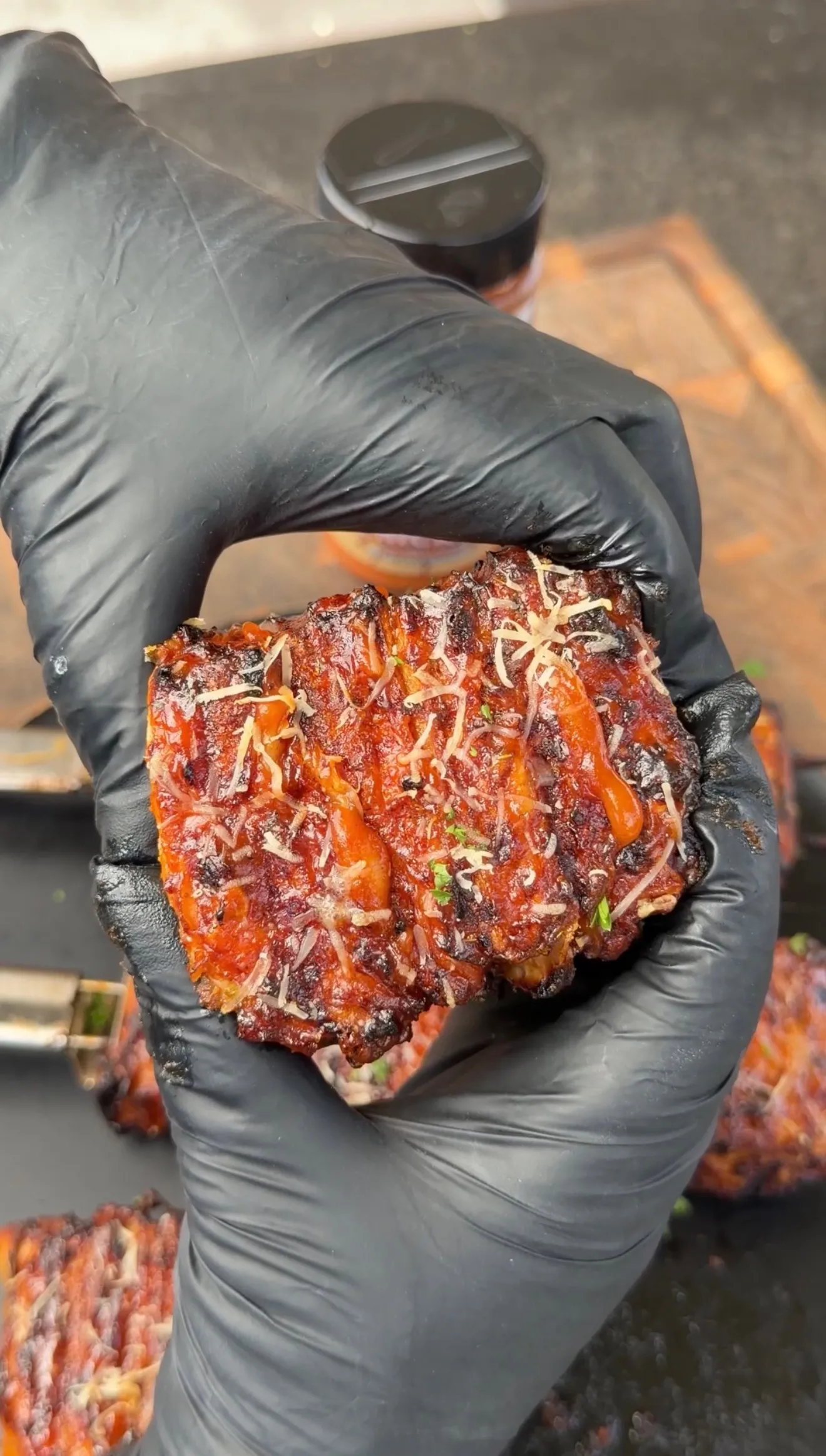 Buffalo chicken tortilla kebabs with melted cheese and herbs being held in black gloved hands