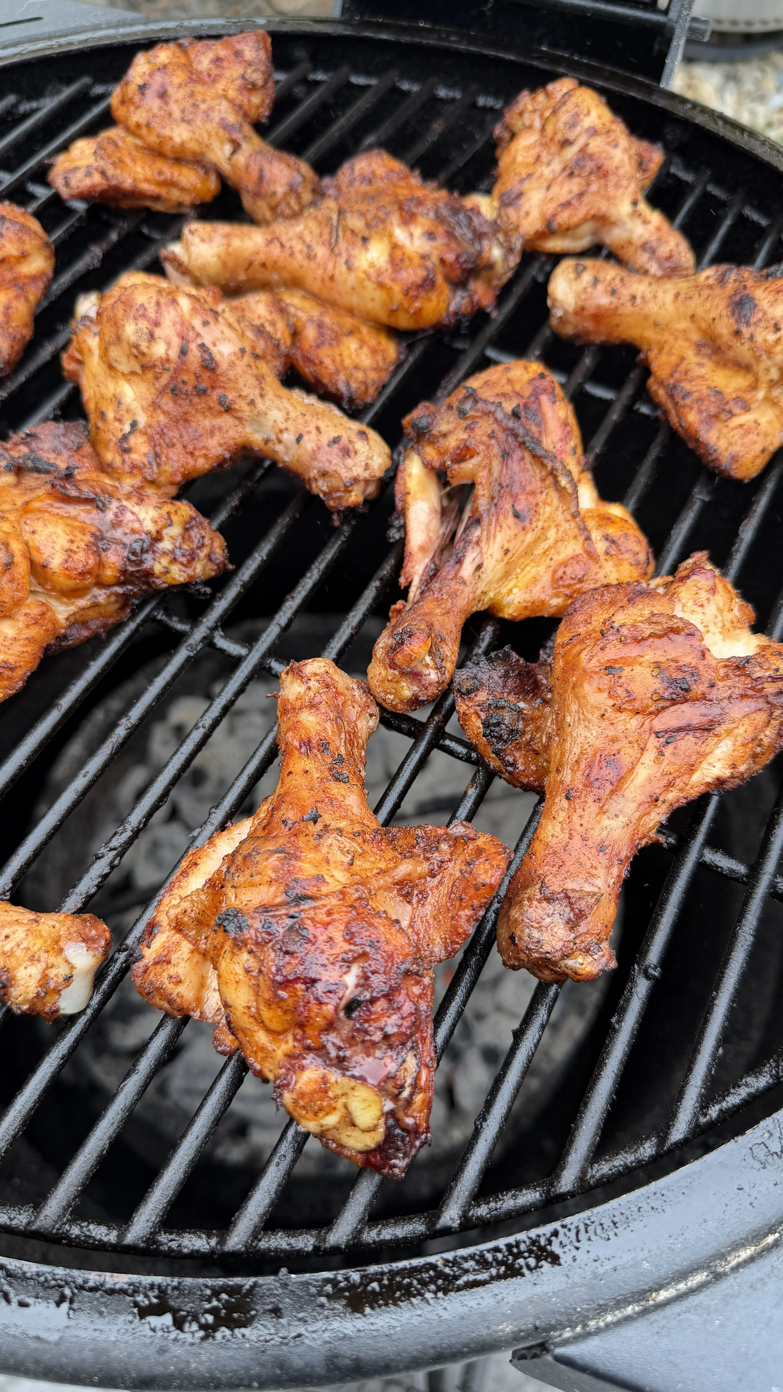 Butter chili lime grilled chicken drumsticks cooking on a charcoal grill with golden-brown, spiced crust